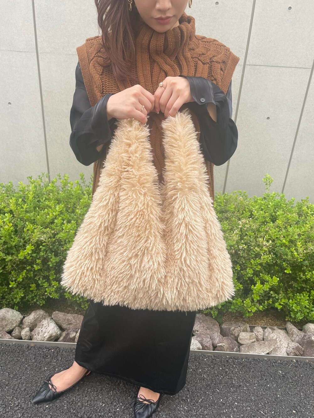 イエロー系のベスト、ベージュ系のトートバッグ、ブラック系のスカートを着用したレディースの秋コーディネートの2枚目の写真