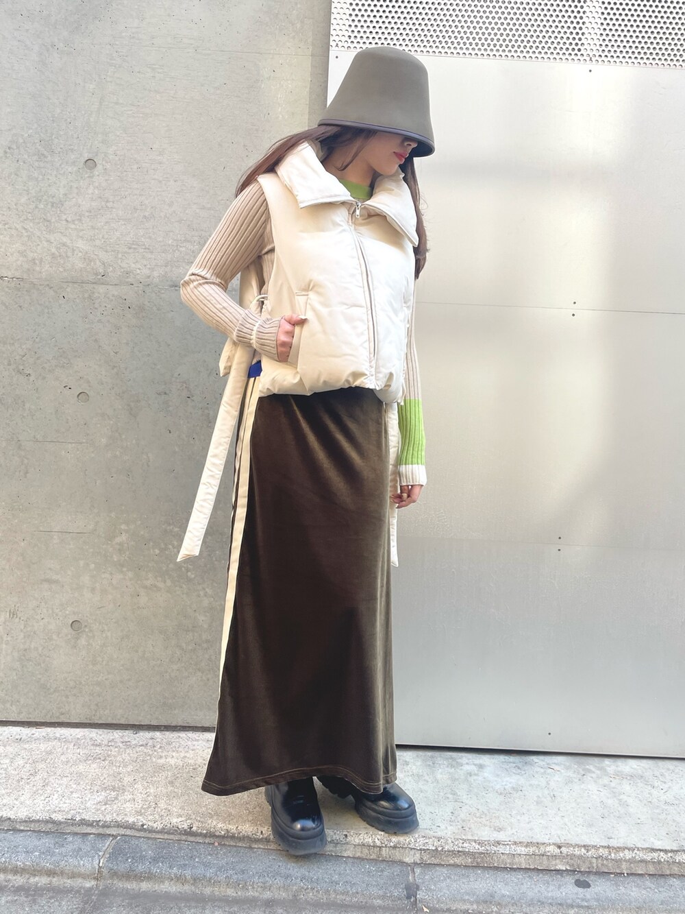 グリーン系のスカート、ベージュ系のニット/セーター、ホワイト系のダウンベストを着用したレディースの冬コーディネートの5枚目の写真
