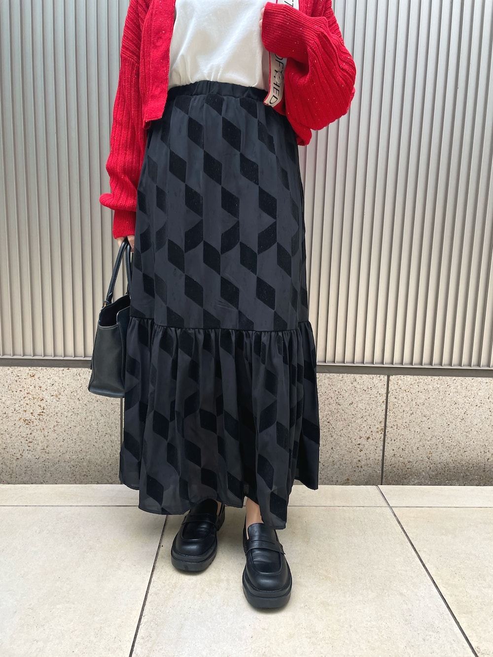 ブラック系のバッグ、ブラック系のスカート、レッド系のカーディガン/ボレロを着用したレディースの冬コーディネートの3枚目の写真