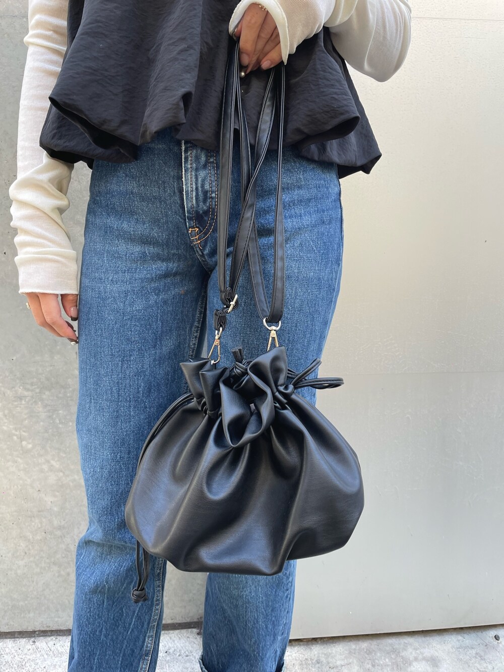 ホワイト系のTシャツ/カットソー、ブラック系のショルダーバッグ、ブルー系のデニムパンツを着用したレディースの春コーディネートの5枚目の写真