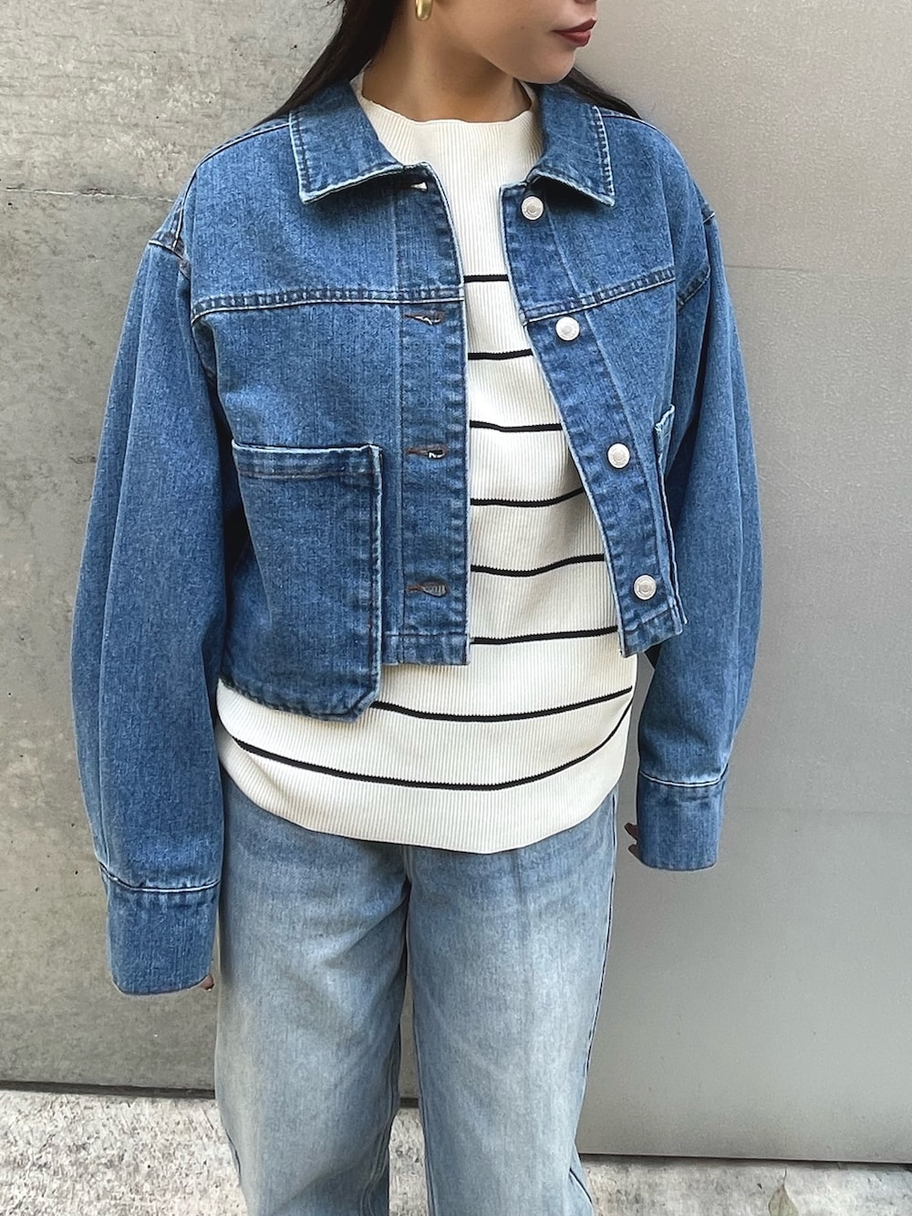 ブルー系のデニムジャケット、ブラック系のスニーカー、ブルー系のデニムパンツを着用したレディースの春コーディネートの2枚目の写真