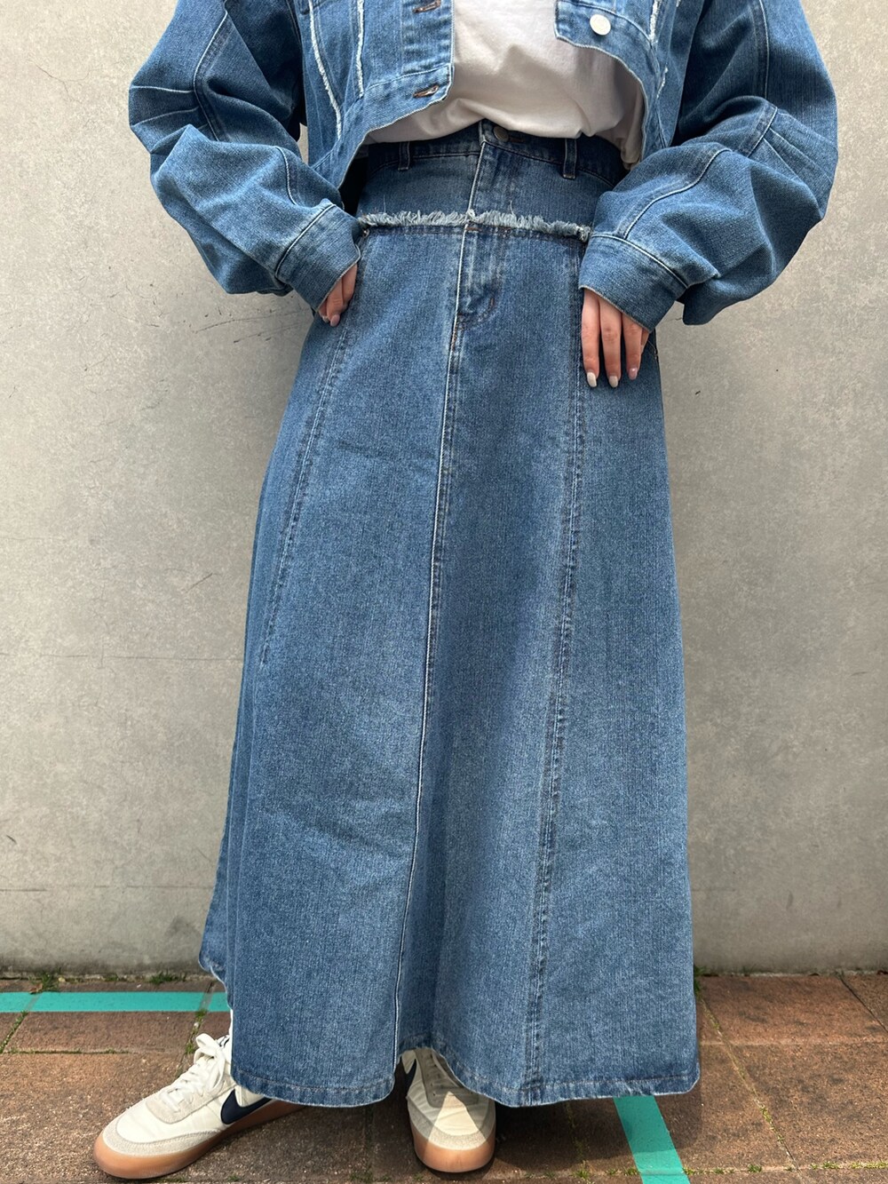 ブルー系のデニムジャケット、ブルー系のスカート、ホワイト系のスニーカーを着用したレディースの春コーディネートの4枚目の写真