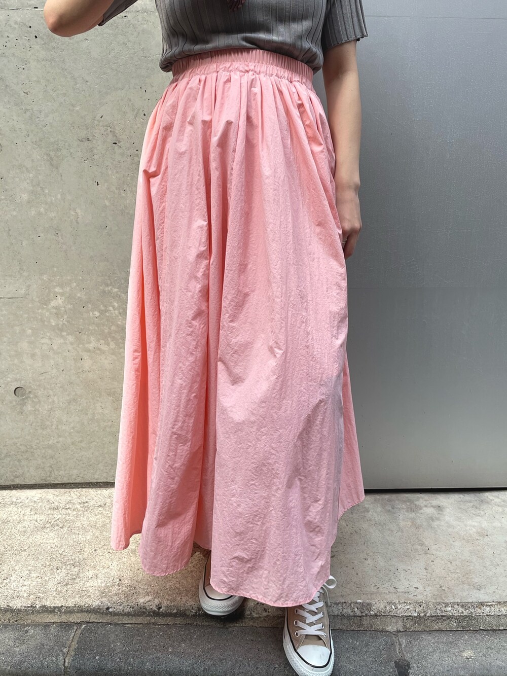 ベージュ系のスニーカー、ピンク系のスカートを着用したレディースの春コーディネートの3枚目の写真