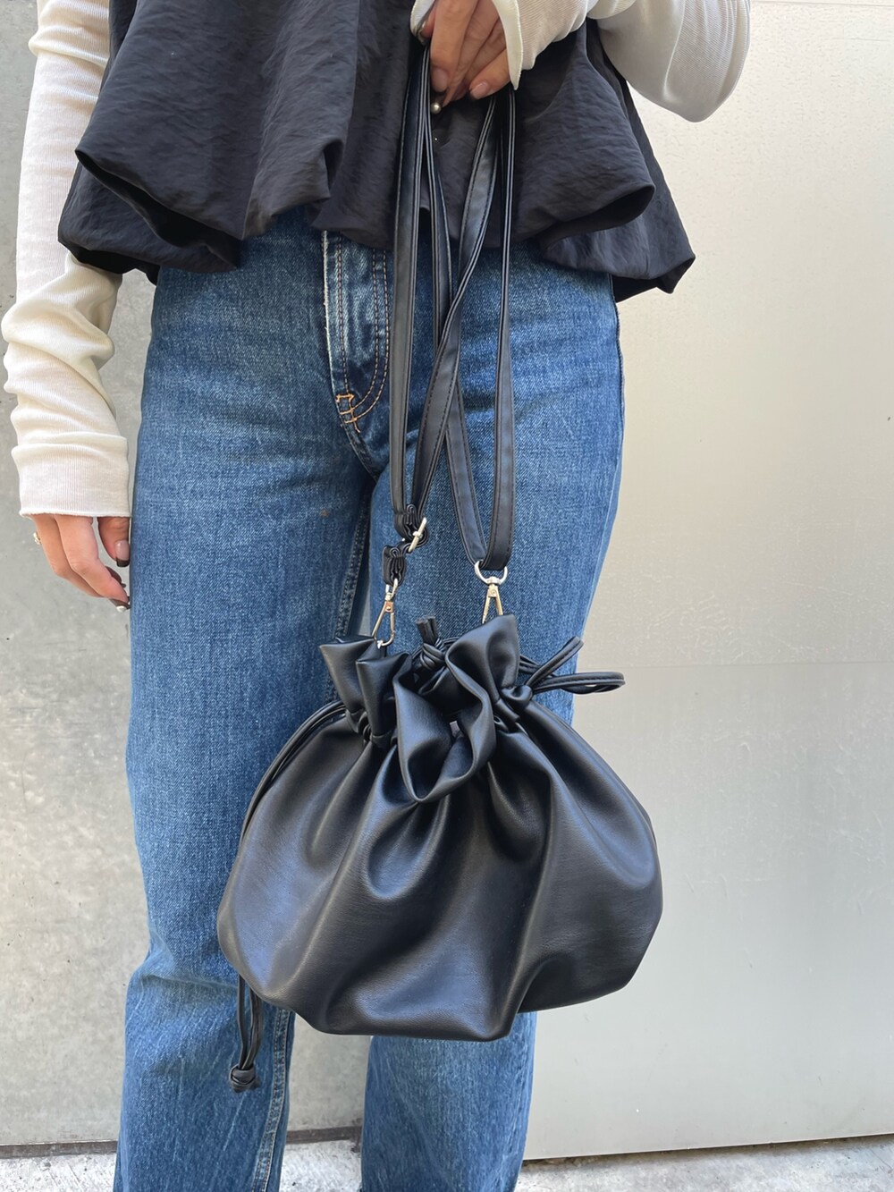 ホワイト系のTシャツ/カットソー、ブラック系のショルダーバッグ、ブラック系のベストを着用したレディースの春コーディネートの5枚目の写真