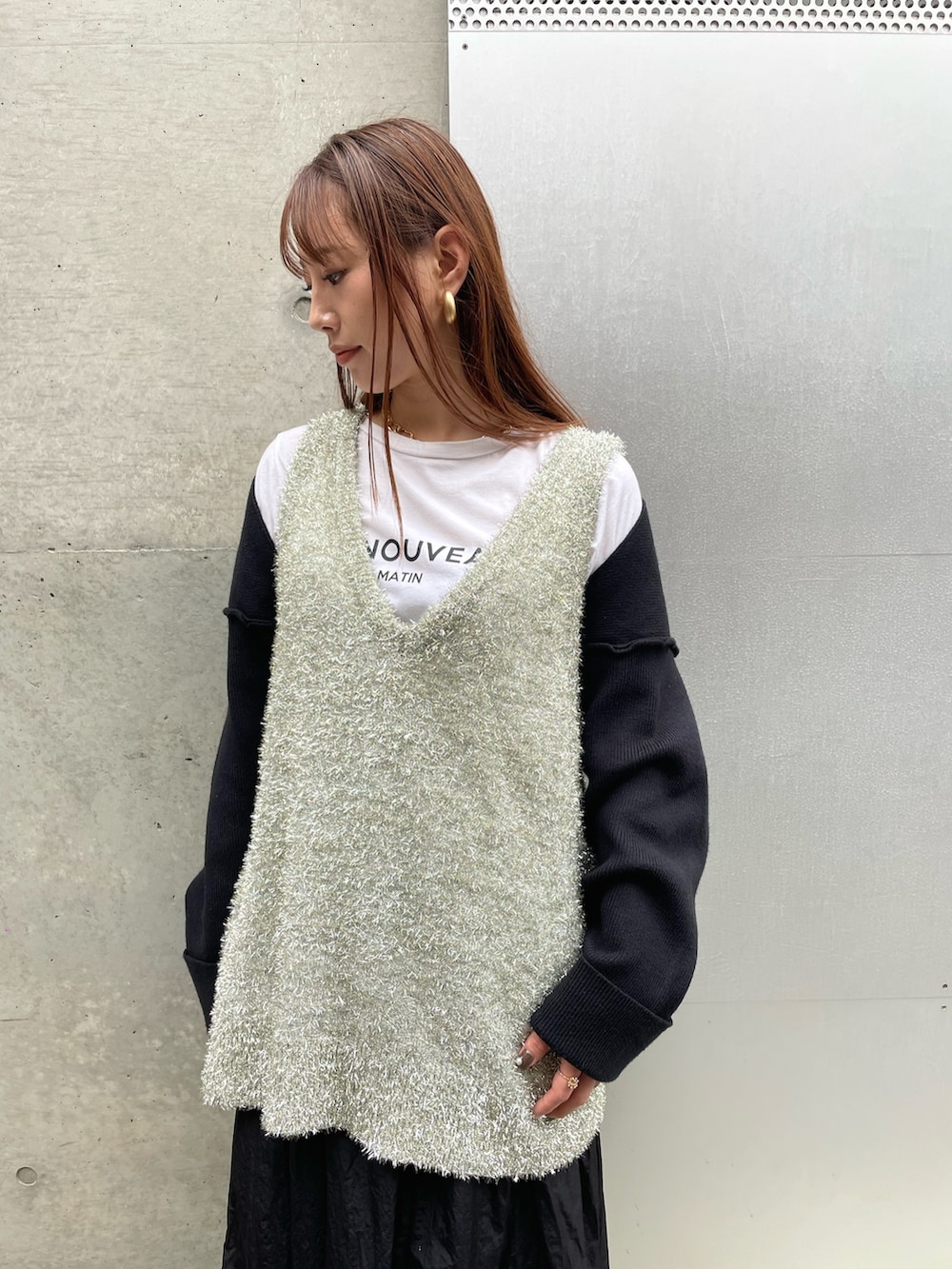 ゴールド系のベスト、ブラック系のスカートを着用したレディースの冬コーディネートの2枚目の写真