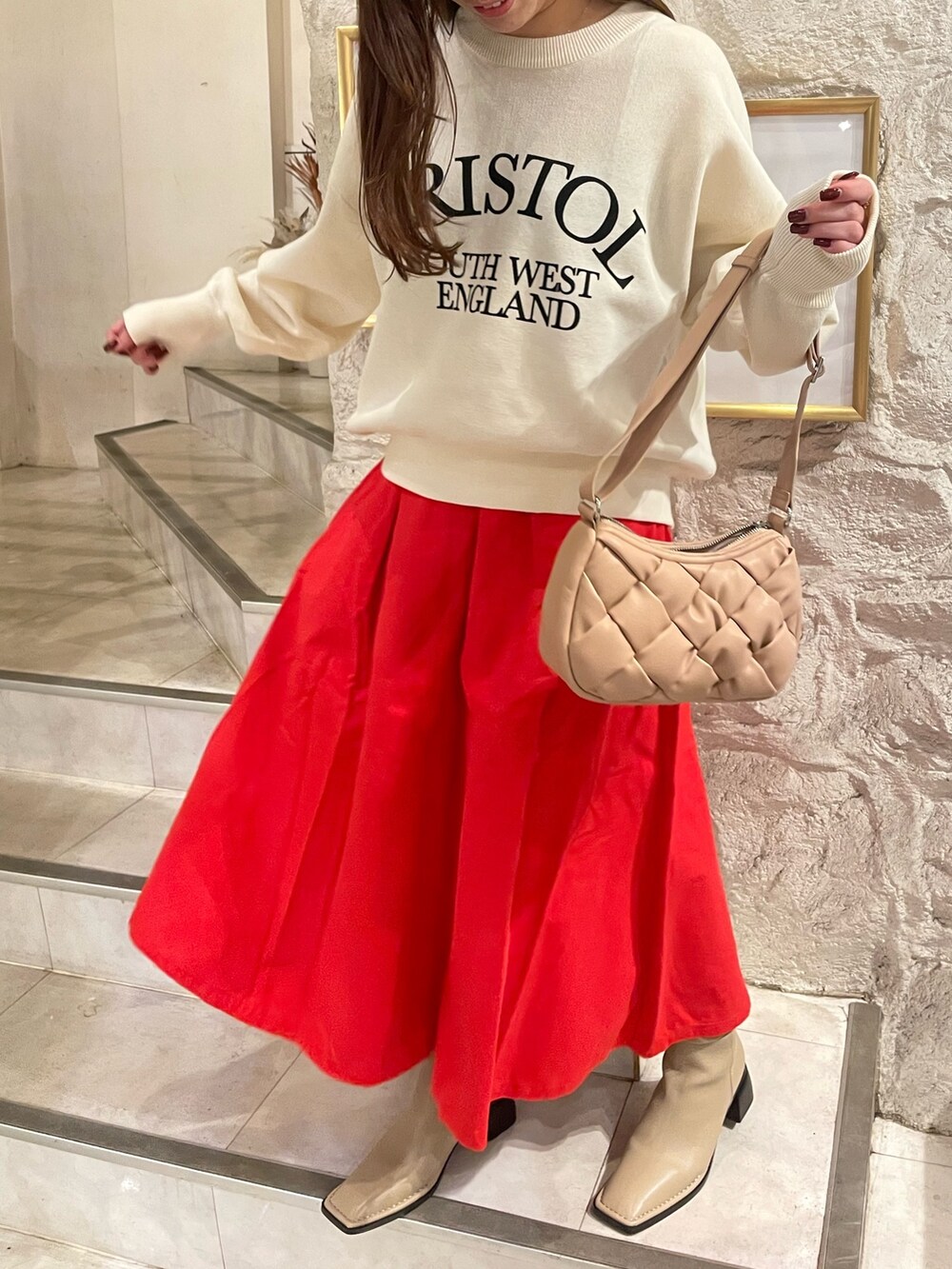 ホワイト系のニット/セーター、レッド系のスカートを着用したレディースの秋コーディネートの5枚目の写真