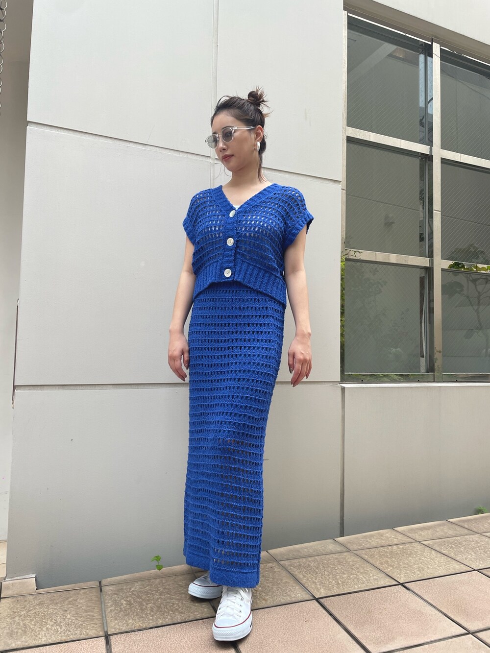 ブルー系のスカート、ブルー系のベスト、ホワイト系のスニーカーを着用したレディースの春コーディネートの2枚目の写真