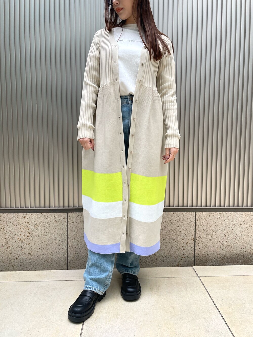 ベージュ系のワンピース、ブルー系のデニムパンツを着用したレディースの冬コーディネートの3枚目の写真