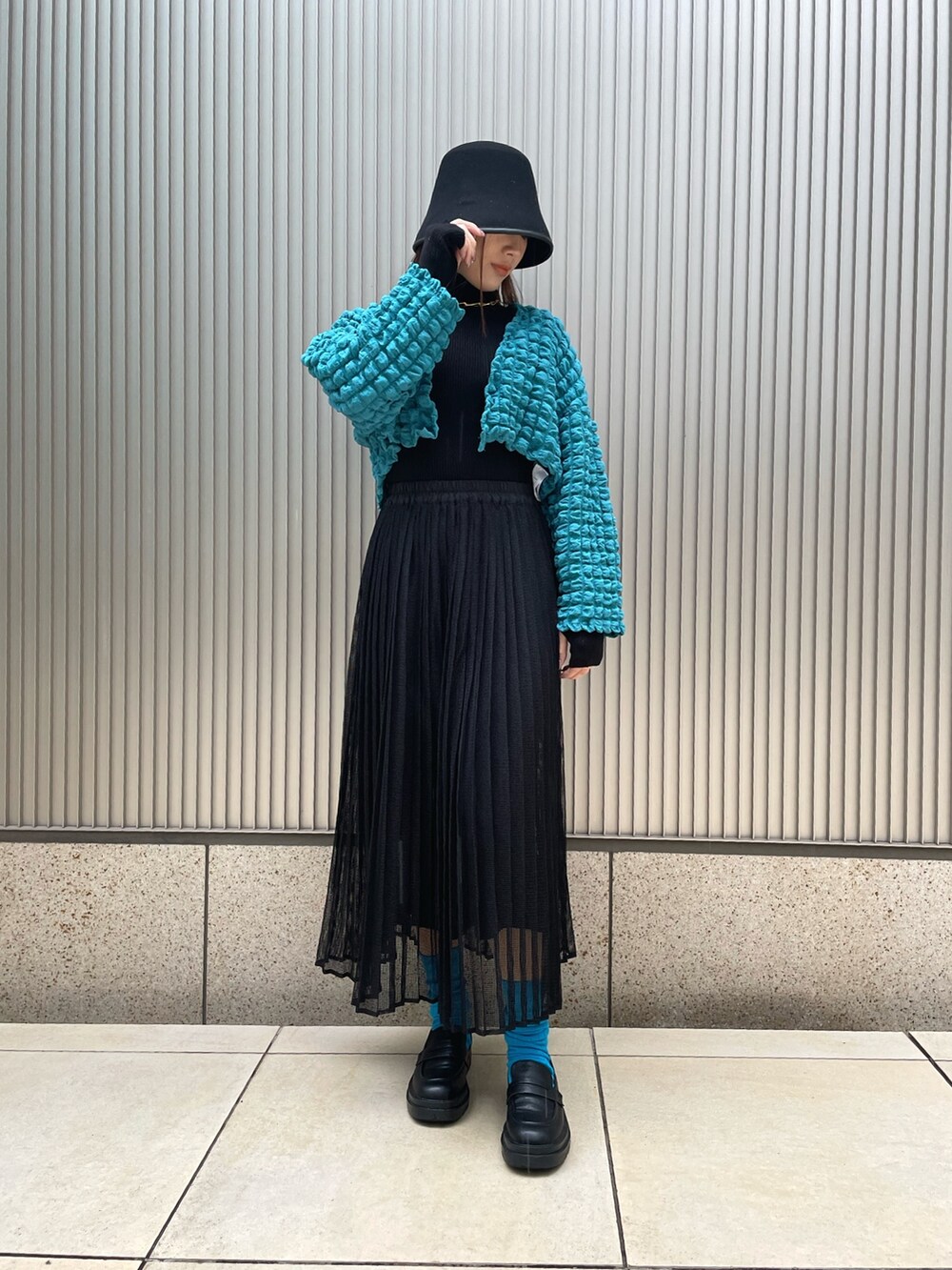 ブラック系のニット/セーター、ブルー系のカーディガン/ボレロ、ブラック系のスカートを着用したレディースの冬コーディネートの2枚目の写真