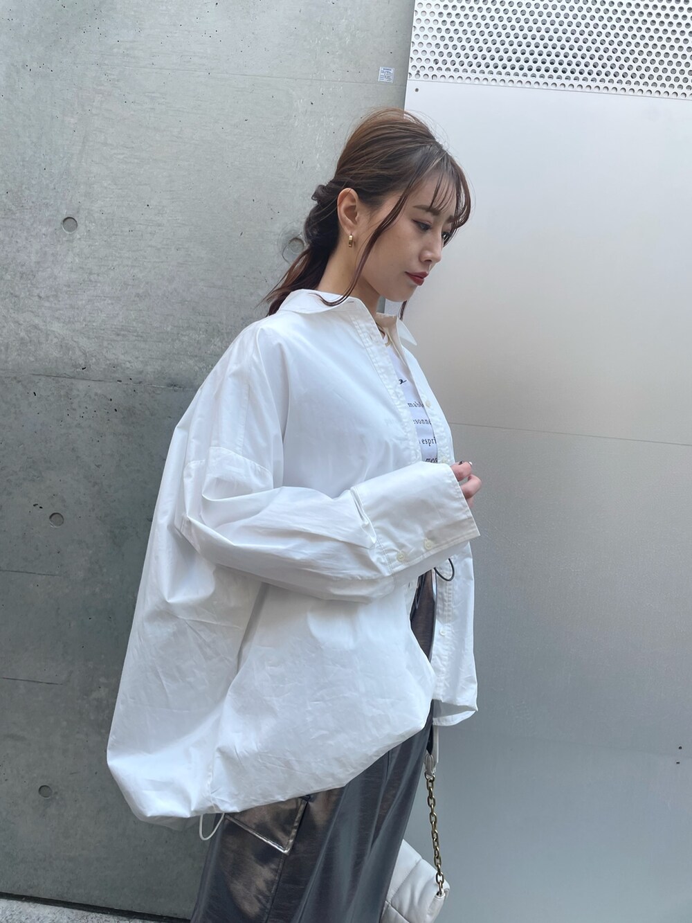 ホワイト系のスニーカー、ホワイト系のバッグ、シルバー系のスカートを着用したレディースの春コーディネートの3枚目の写真