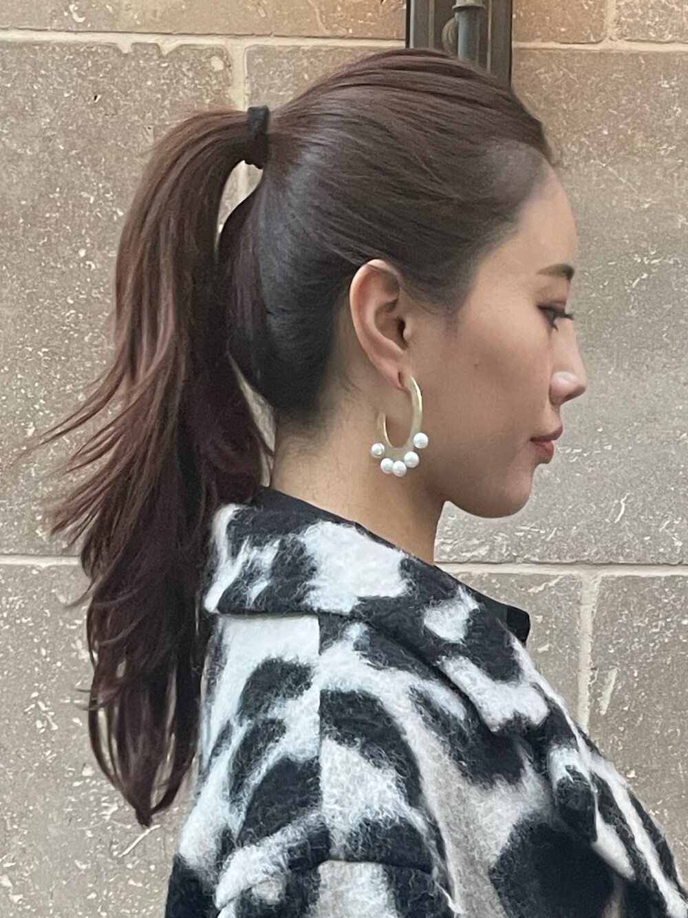 ベージュ系のチェスターコート、ゴールド系のピアス（両耳用）を着用したレディースの秋コーディネートの9枚目の写真