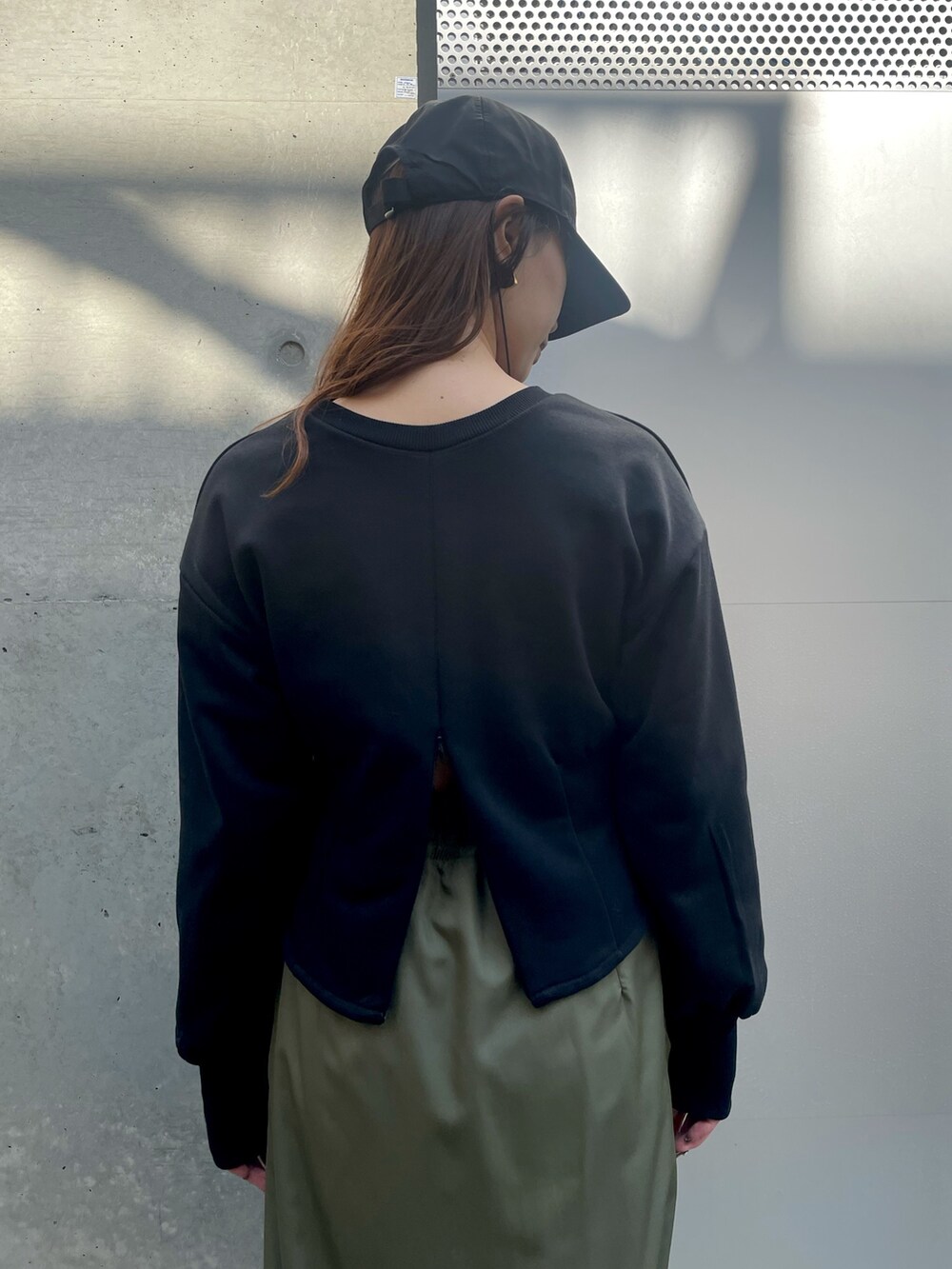 ブラック系のスウェット、グリーン系のスカートを着用したレディースの春コーディネートの3枚目の写真