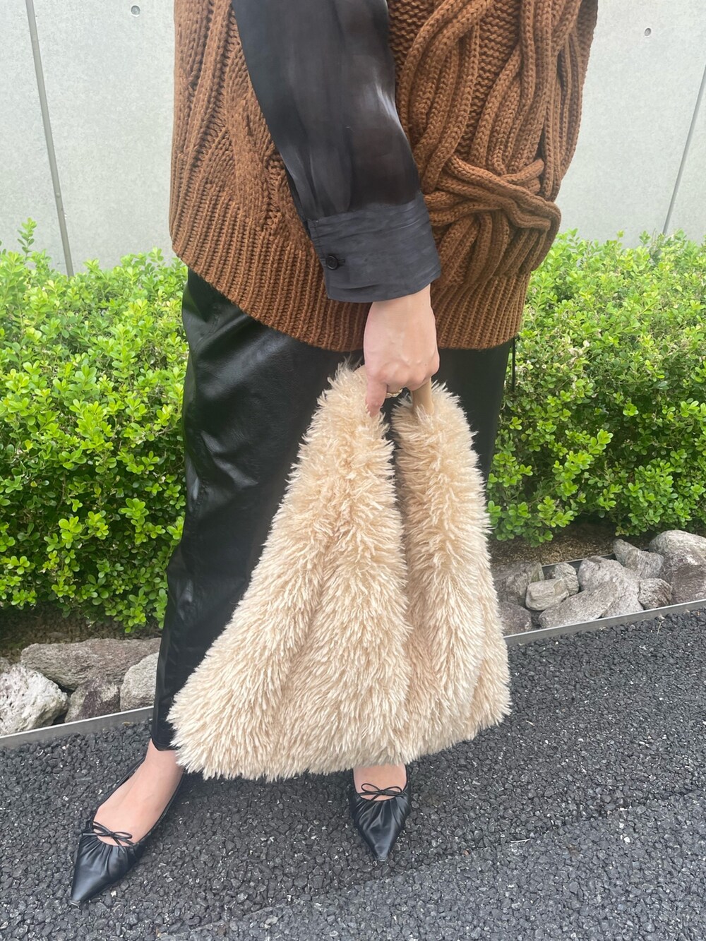 イエロー系のベスト、ベージュ系のトートバッグ、ブラック系のスカートを着用したレディースの秋コーディネートの3枚目の写真