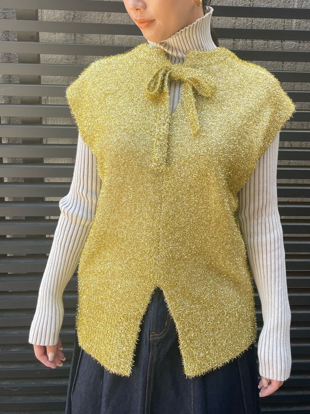 ブルー系のデニムスカート、ホワイト系のニット/セーター、ゴールド系のベストを着用したレディースの冬コーディネートの7枚目の写真