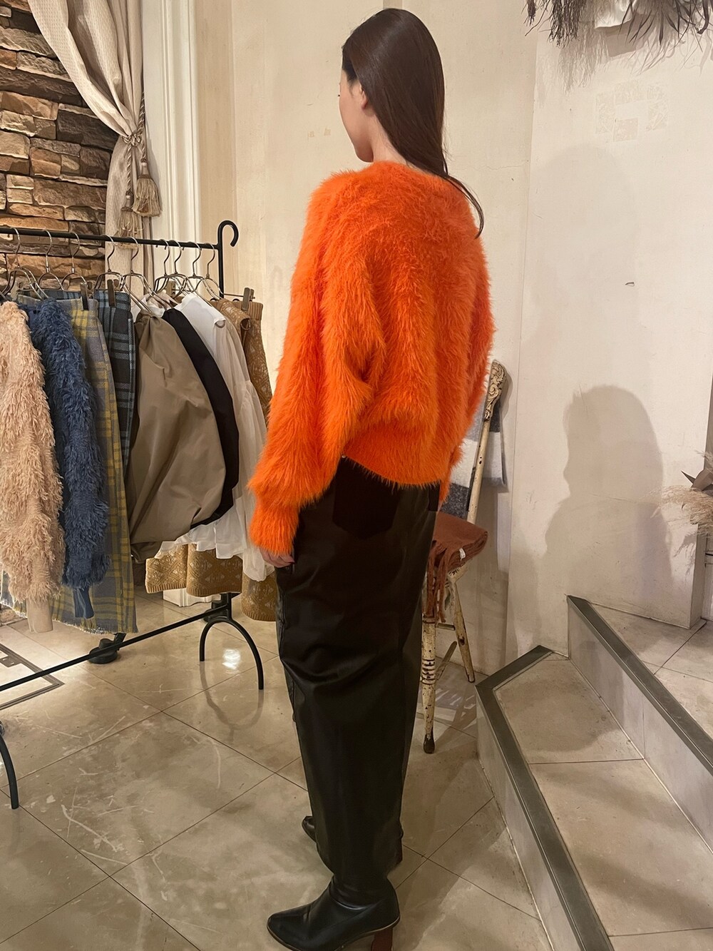 オレンジ系のニット/セーター、ブラック系のスカートを着用したレディースの秋コーディネートの5枚目の写真