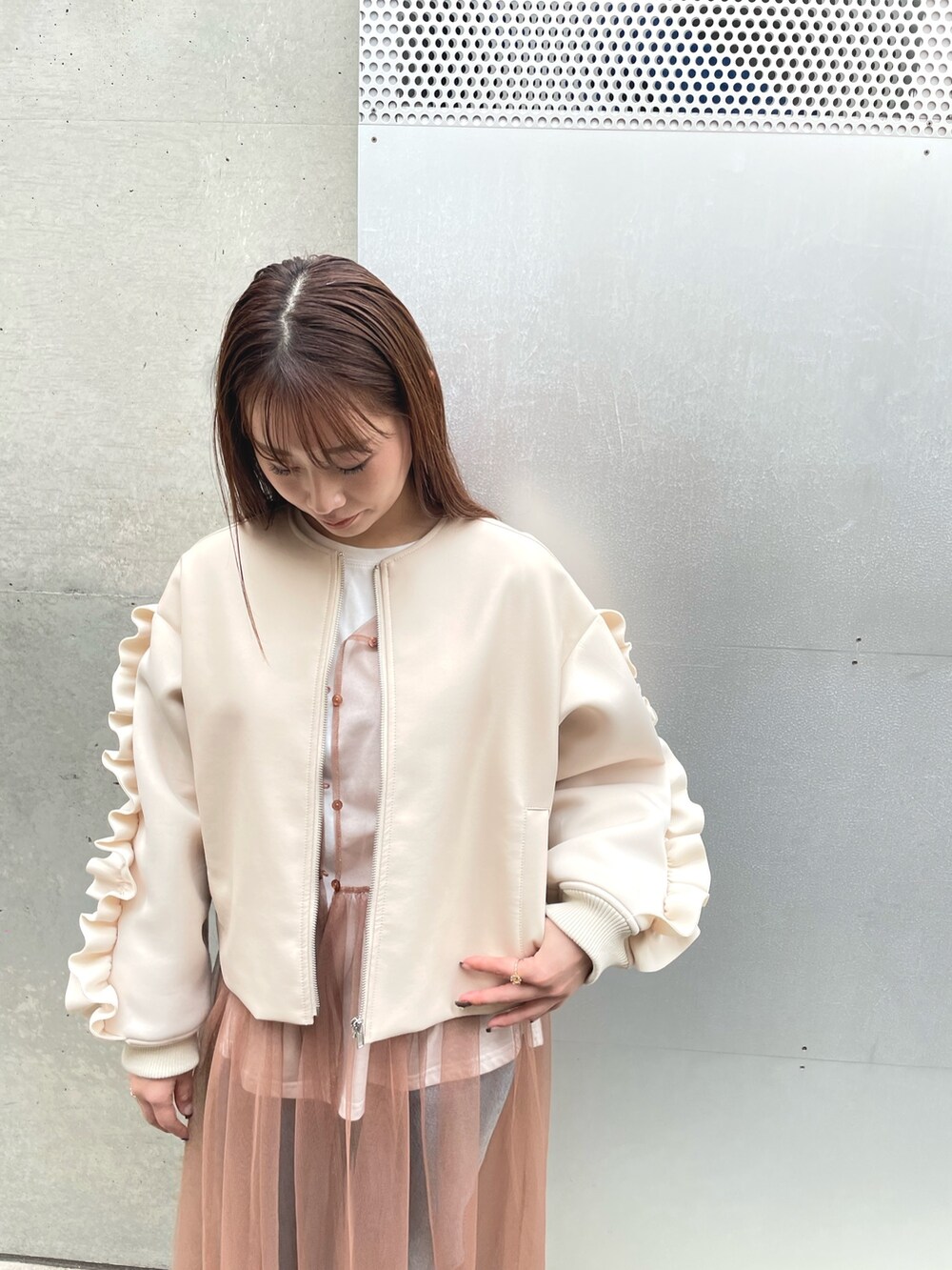 ホワイト系のブルゾン、ベージュ系のワンピースを着用したレディースの冬コーディネートの2枚目の写真