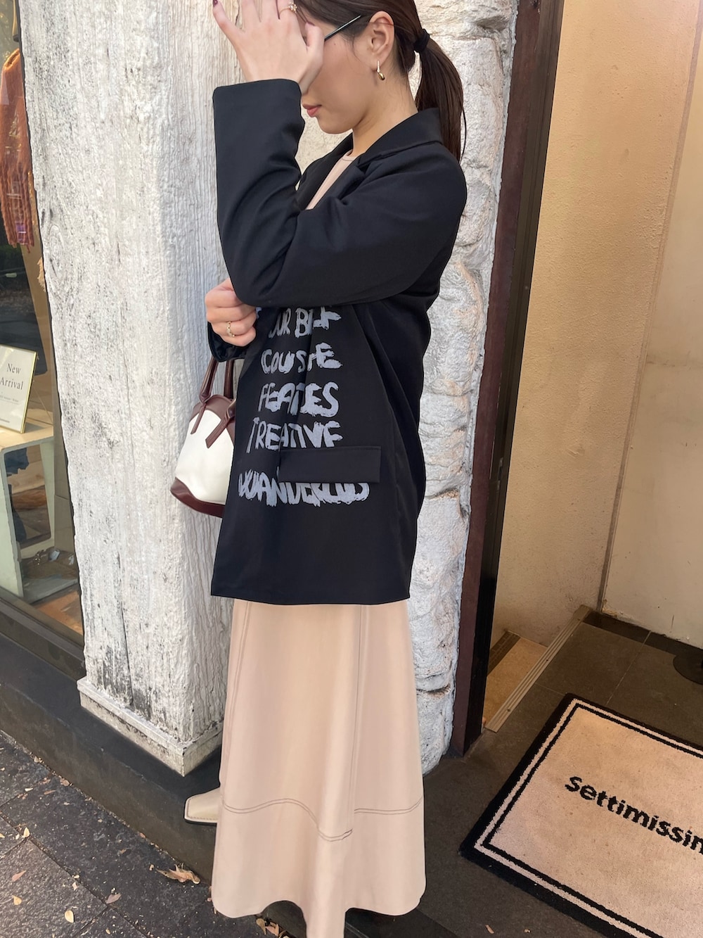 ベージュ系のワンピース、ブラウン系のハンドバッグ、ブラック系のサングラスを着用したレディースの秋コーディネートの5枚目の写真