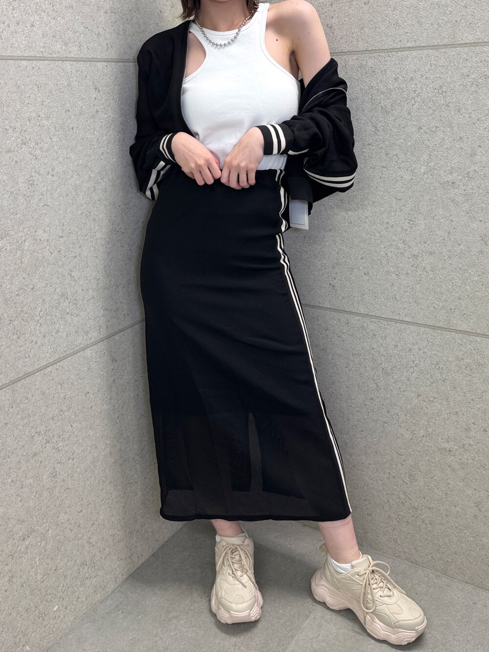 ブラック系のスカート、ホワイト系のタンクトップ、ブラック系のブルゾンを着用したレディースの春コーディネートの4枚目の写真