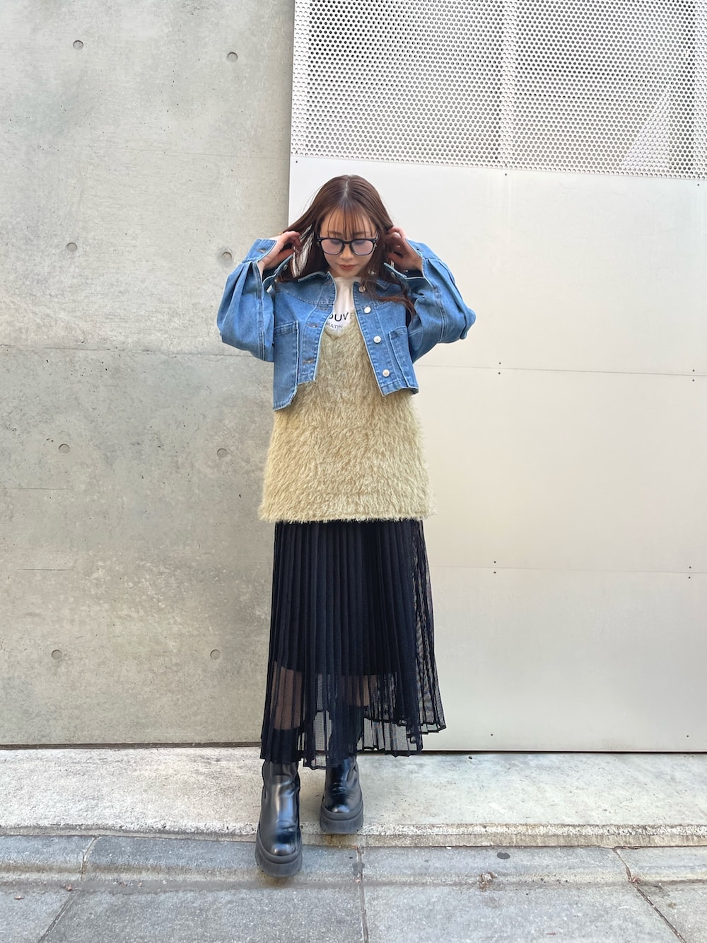 グリーン系のベスト、ブラック系のスカート、ブルー系のデニムジャケットを着用したレディースの冬コーディネートの2枚目の写真