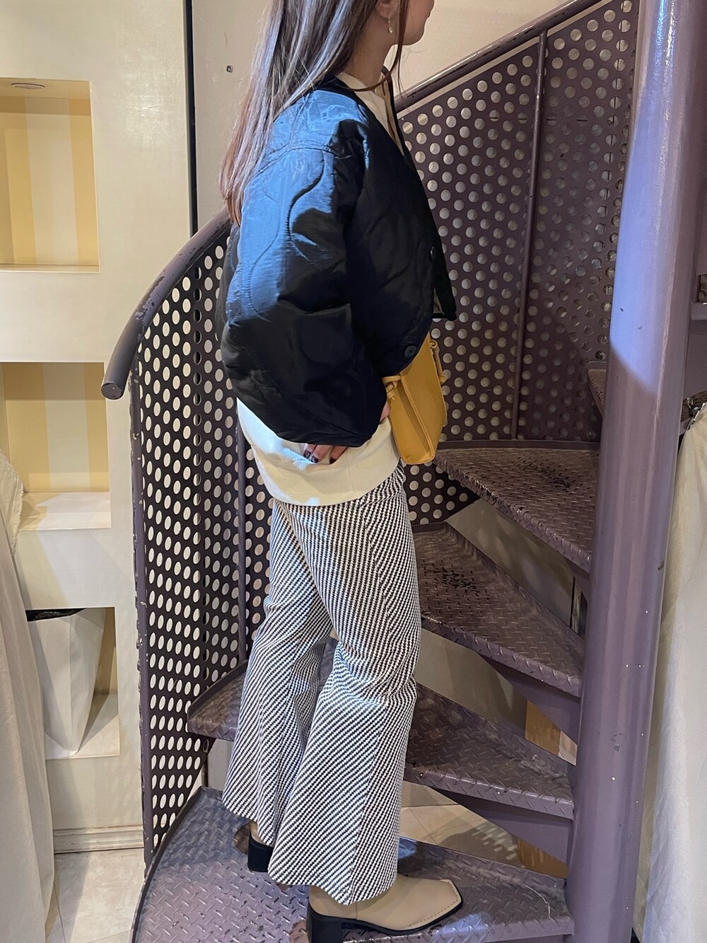 ブラック系のその他アウター、ホワイト系のニット/セーター、ベージュ系のショルダーバッグを着用したレディースの秋コーディネートの2枚目の写真