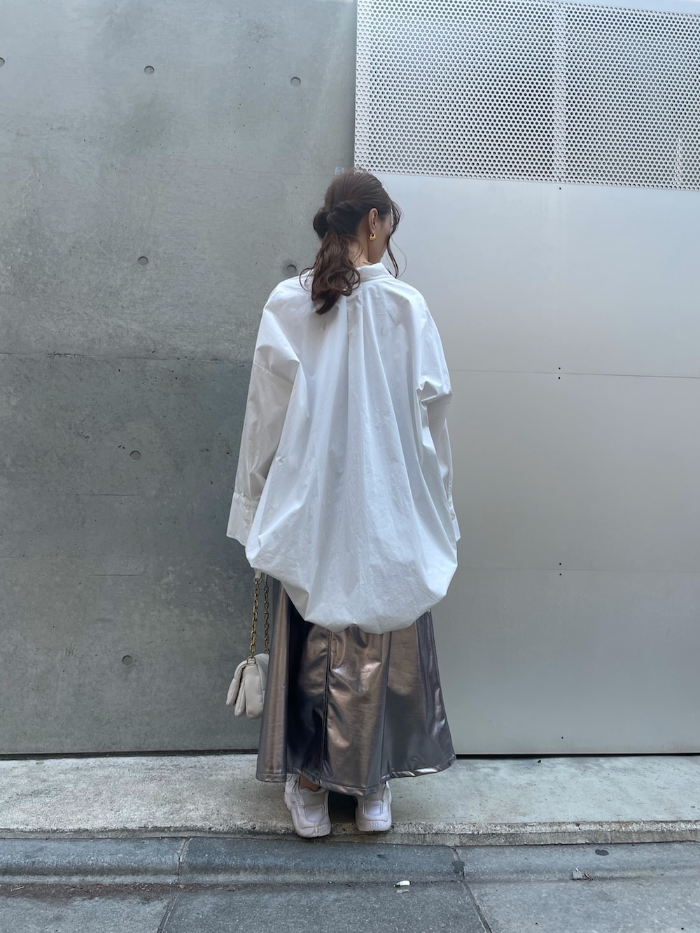 ホワイト系のハンドバッグ、ホワイト系のスニーカー、シルバー系のスカートを着用したレディースの春コーディネートの6枚目の写真