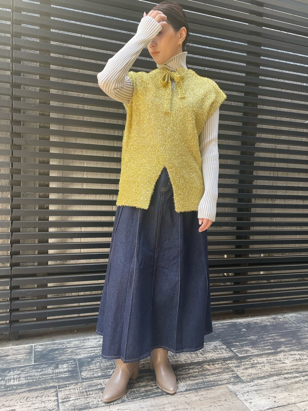 ブルー系のデニムスカート、ホワイト系のニット/セーター、ゴールド系のベストを着用したレディースの冬コーディネートの4枚目の写真