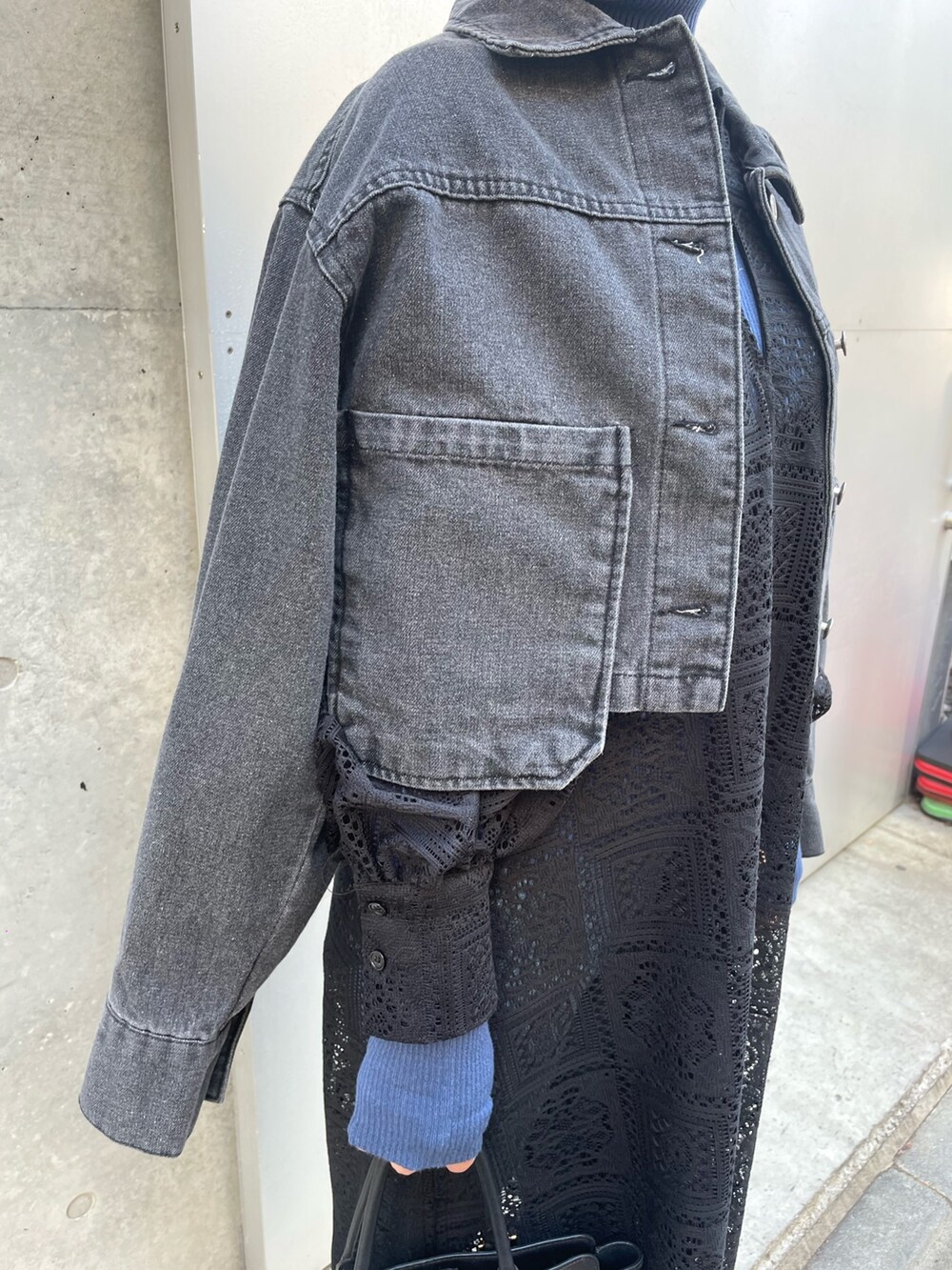 ブラック系のデニムジャケット、ブルー系のニット/セーター、ブラック系のワンピースを着用したレディースの冬コーディネートの4枚目の写真