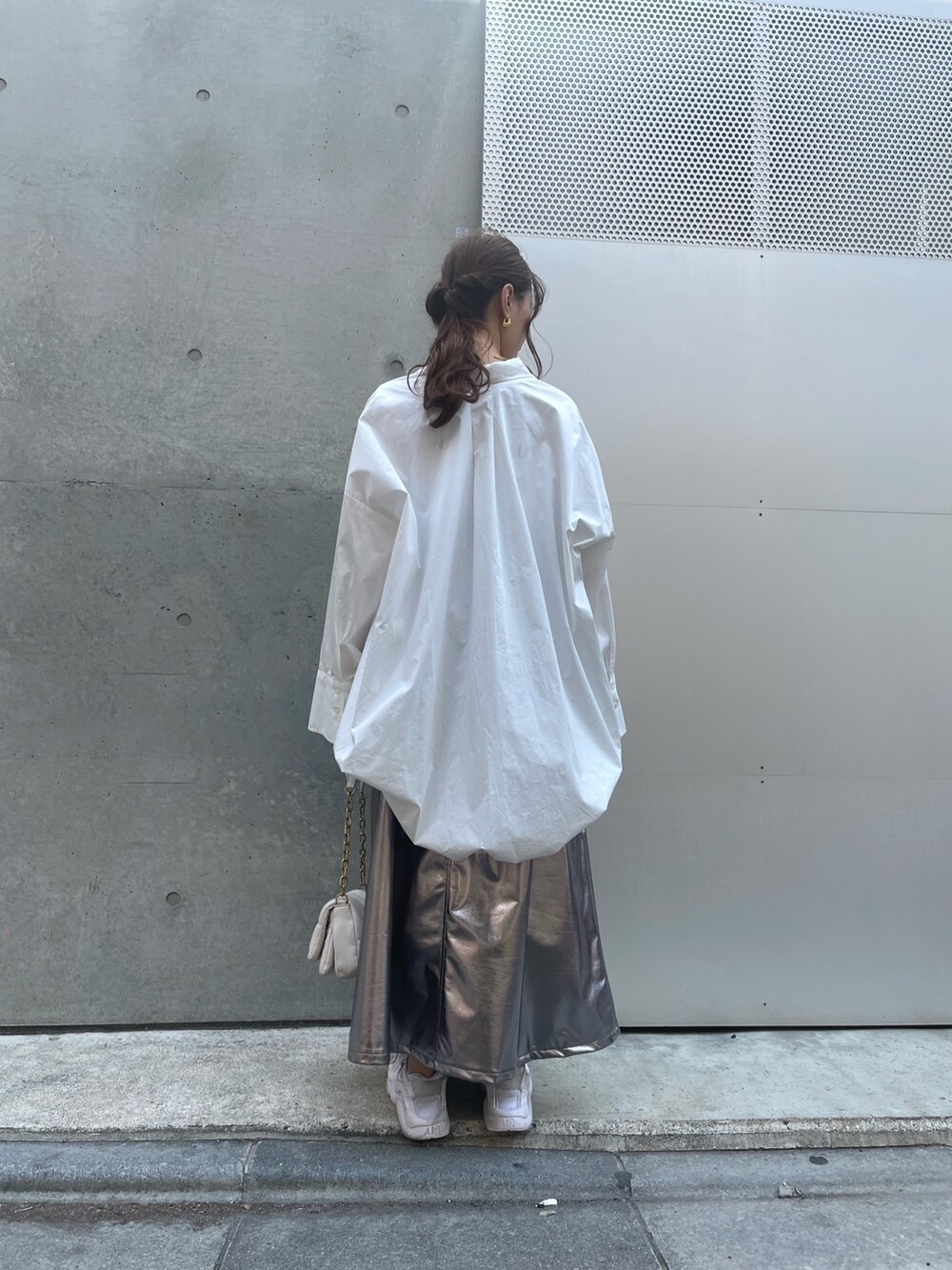 ホワイト系のスニーカー、ホワイト系のバッグ、シルバー系のスカートを着用したレディースの春コーディネートの6枚目の写真