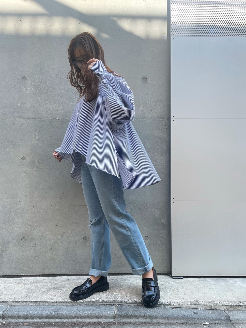 ブルー系のデニムパンツ、ブラック系のローファー、ブラック系のベストを着用したレディースの春コーディネートの5枚目の写真