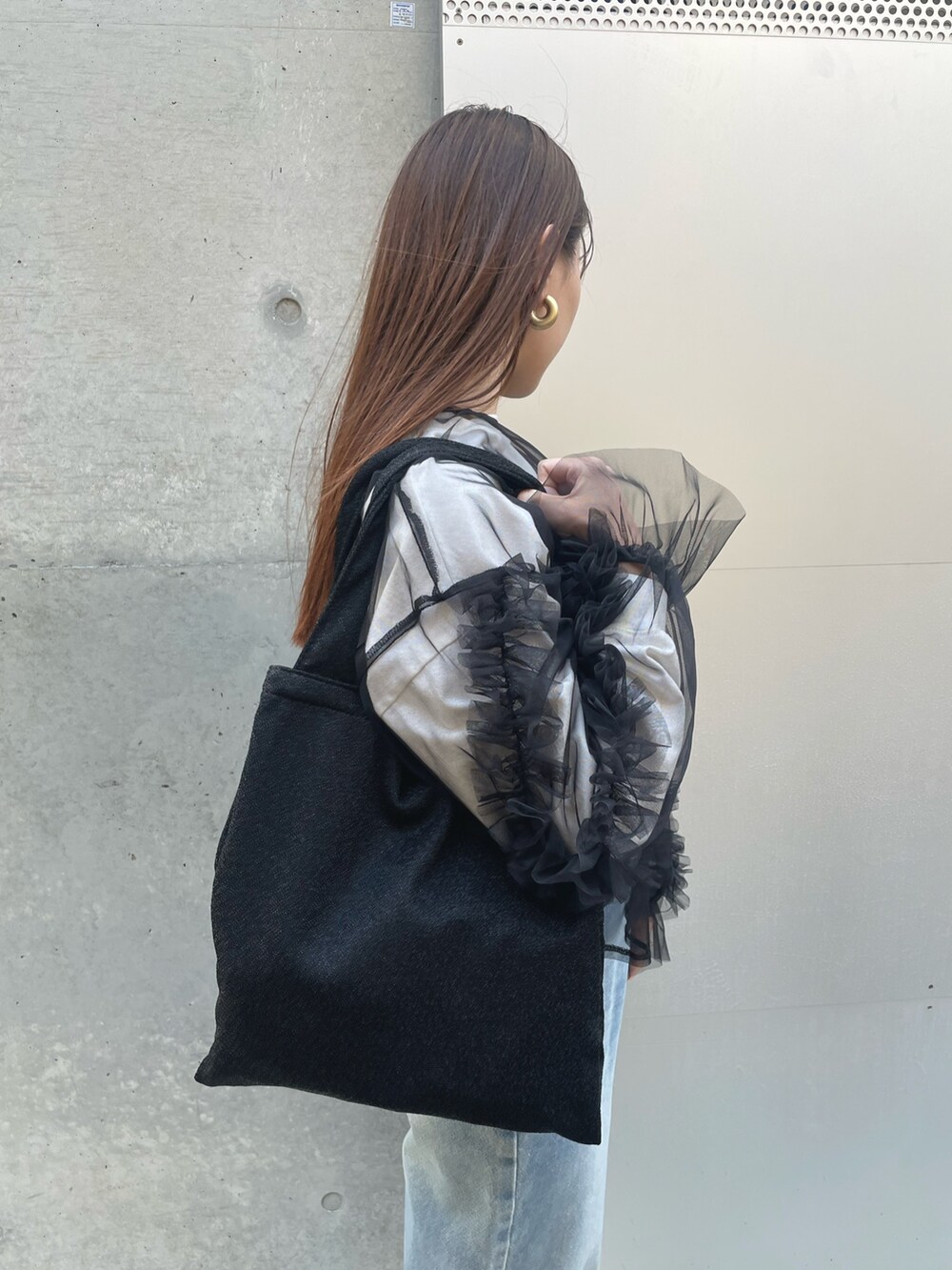 ブルー系のデニムパンツ、ブラック系のTシャツ/カットソー、ブラック系のトートバッグを着用したレディースの春コーディネートの4枚目の写真