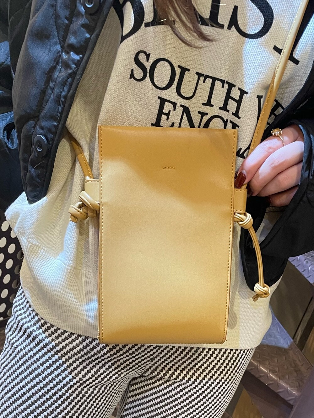 ブラック系のその他アウター、ホワイト系のニット/セーター、ベージュ系のショルダーバッグを着用したレディースの秋コーディネートの7枚目の写真