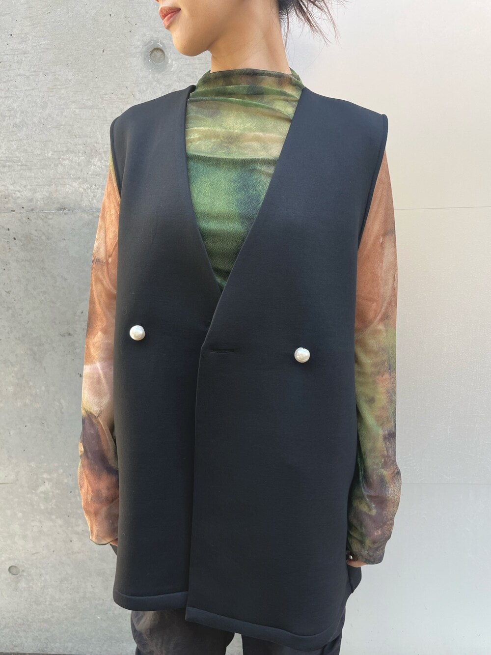 ブラック系のベスト、ブラック系のその他パンツ、グリーン系のTシャツ/カットソーを着用したレディースの春コーディネートの3枚目の写真