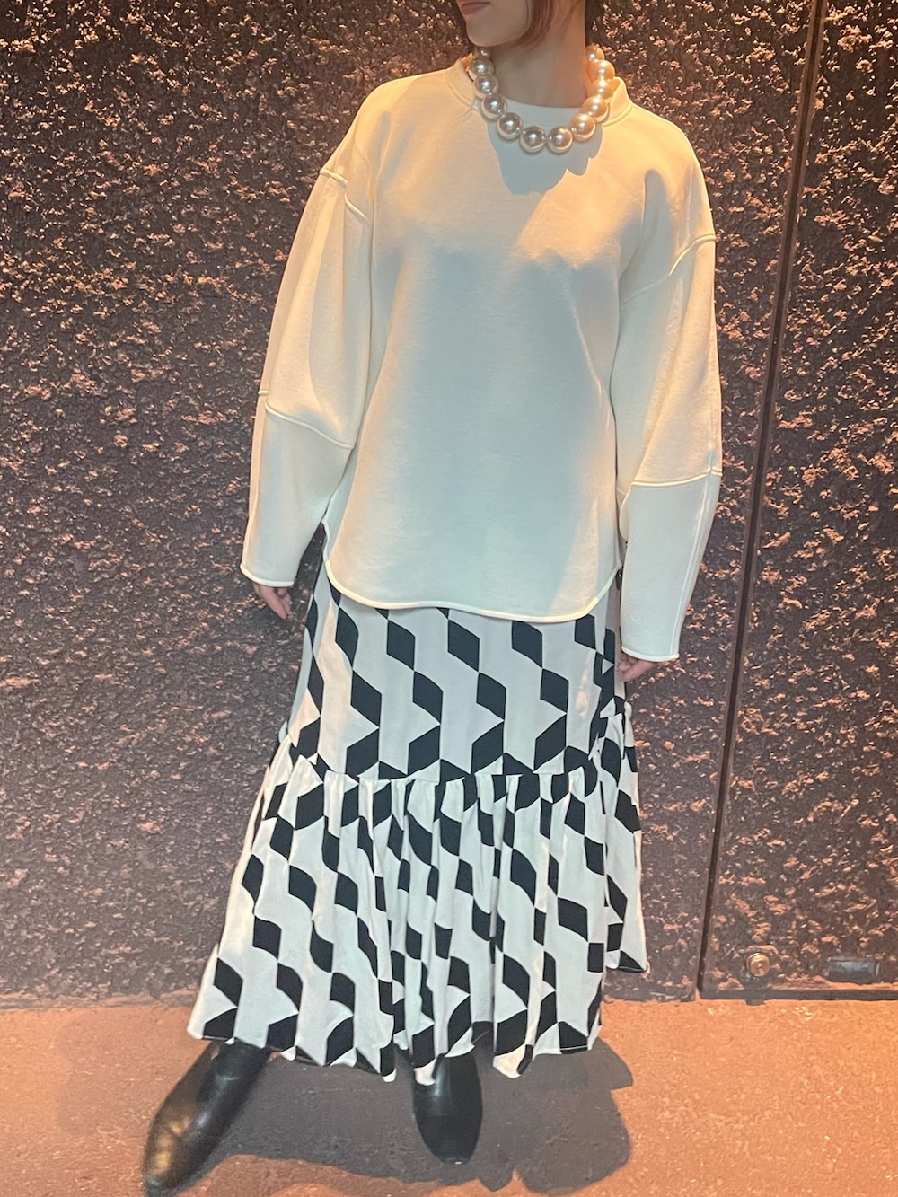 ベージュ系のスカート、ホワイト系のスウェット、その他のネックレスを着用したレディースの秋コーディネートの2枚目の写真