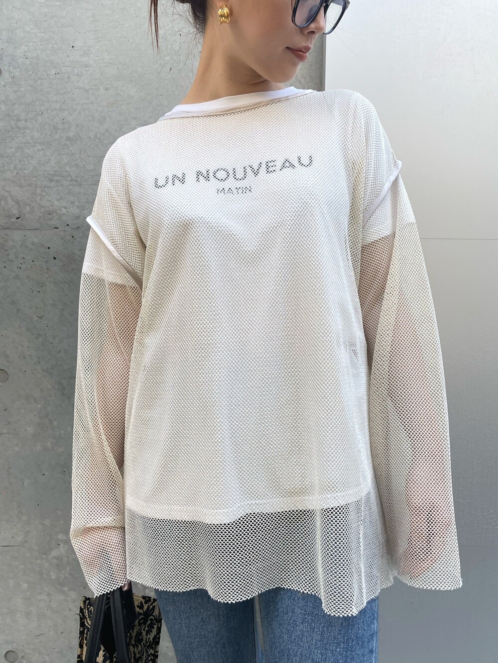 ホワイト系のTシャツ/カットソー、ブルー系のデニムパンツ、ブラック系のブーツを着用したレディースの冬コーディネートの6枚目の写真