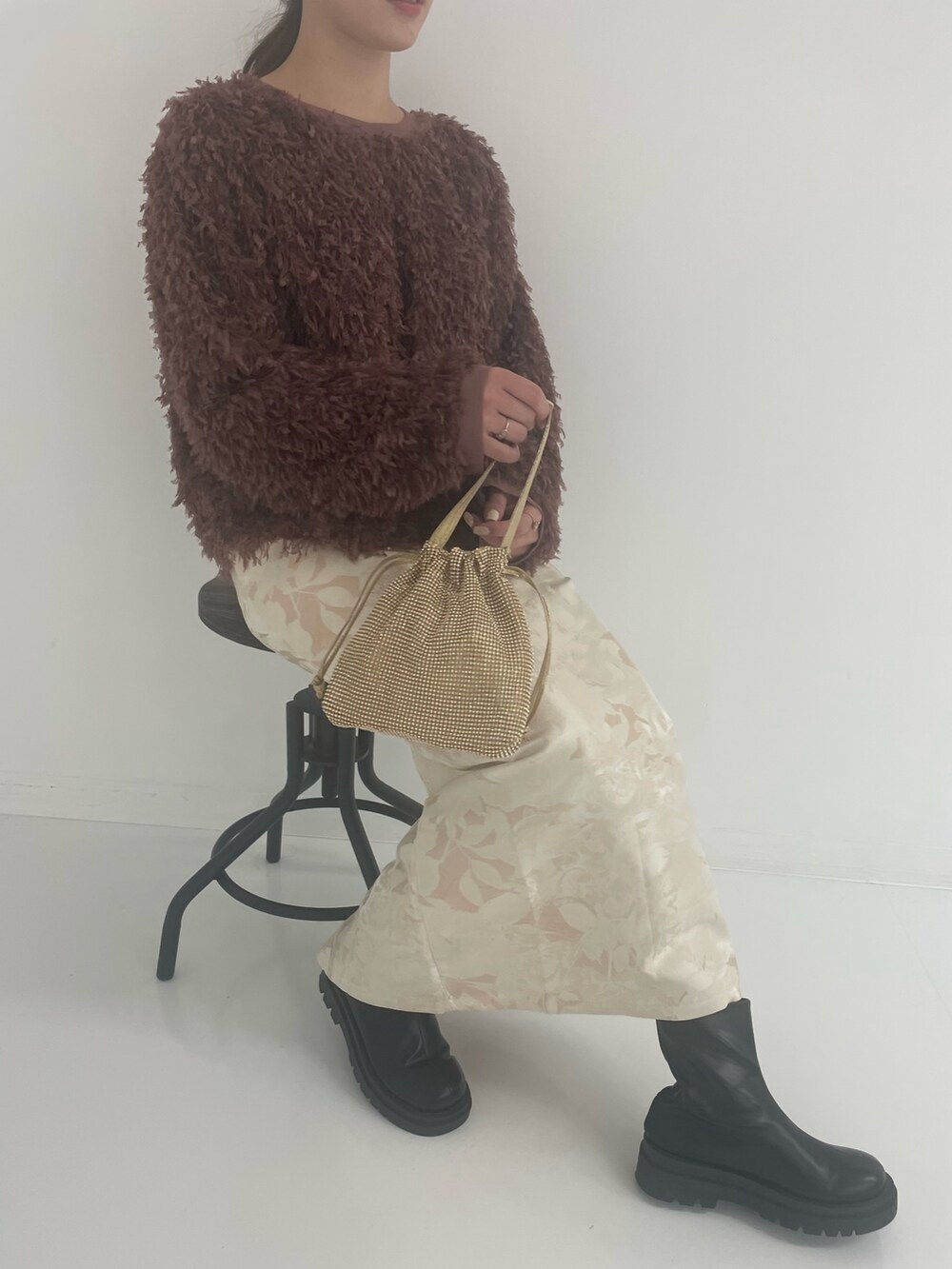 ゴールド系のトートバッグ、ホワイト系のスカート、ブラウン系のTシャツ/カットソーを着用したレディースの冬コーディネートの4枚目の写真