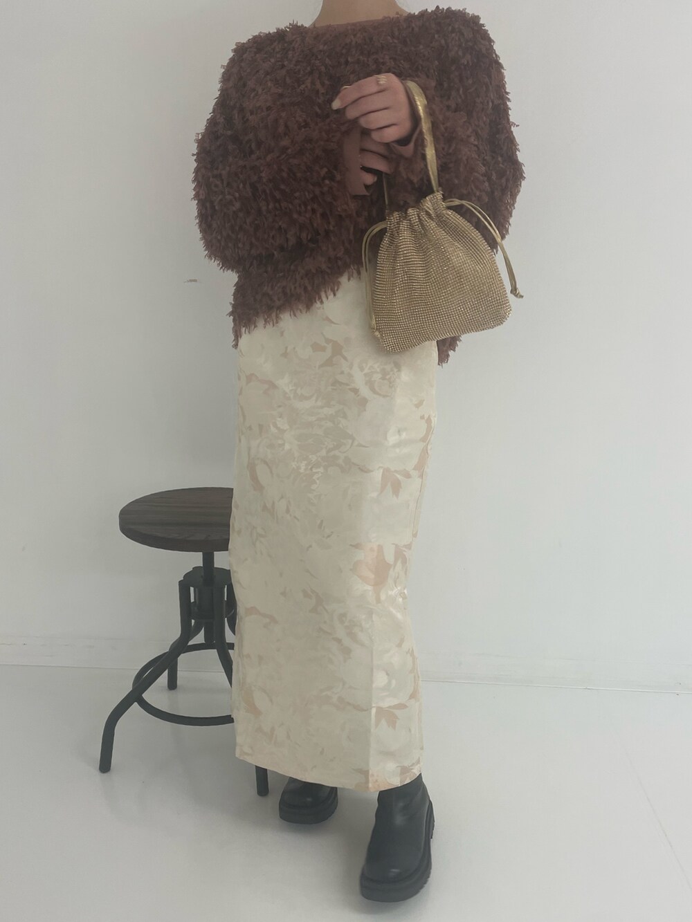 ゴールド系のトートバッグ、ホワイト系のスカート、ブラウン系のTシャツ/カットソーを着用したレディースの冬コーディネートの2枚目の写真