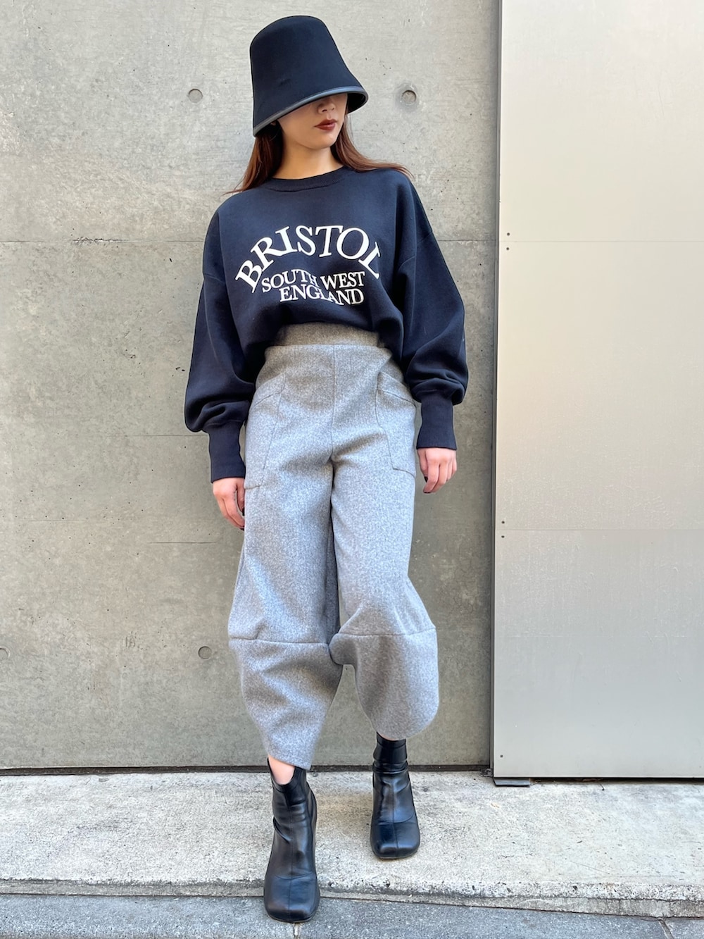 グレー系のその他パンツ、ブラック系のニット/セーター、ブラック系のハットを着用したレディースの冬コーディネートの3枚目の写真