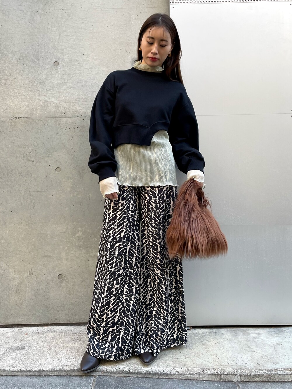 ブラウン系のハンドバッグ、ゴールド系のTシャツ/カットソー、ブラック系のその他パンツを着用したレディースの冬コーディネートの3枚目の写真