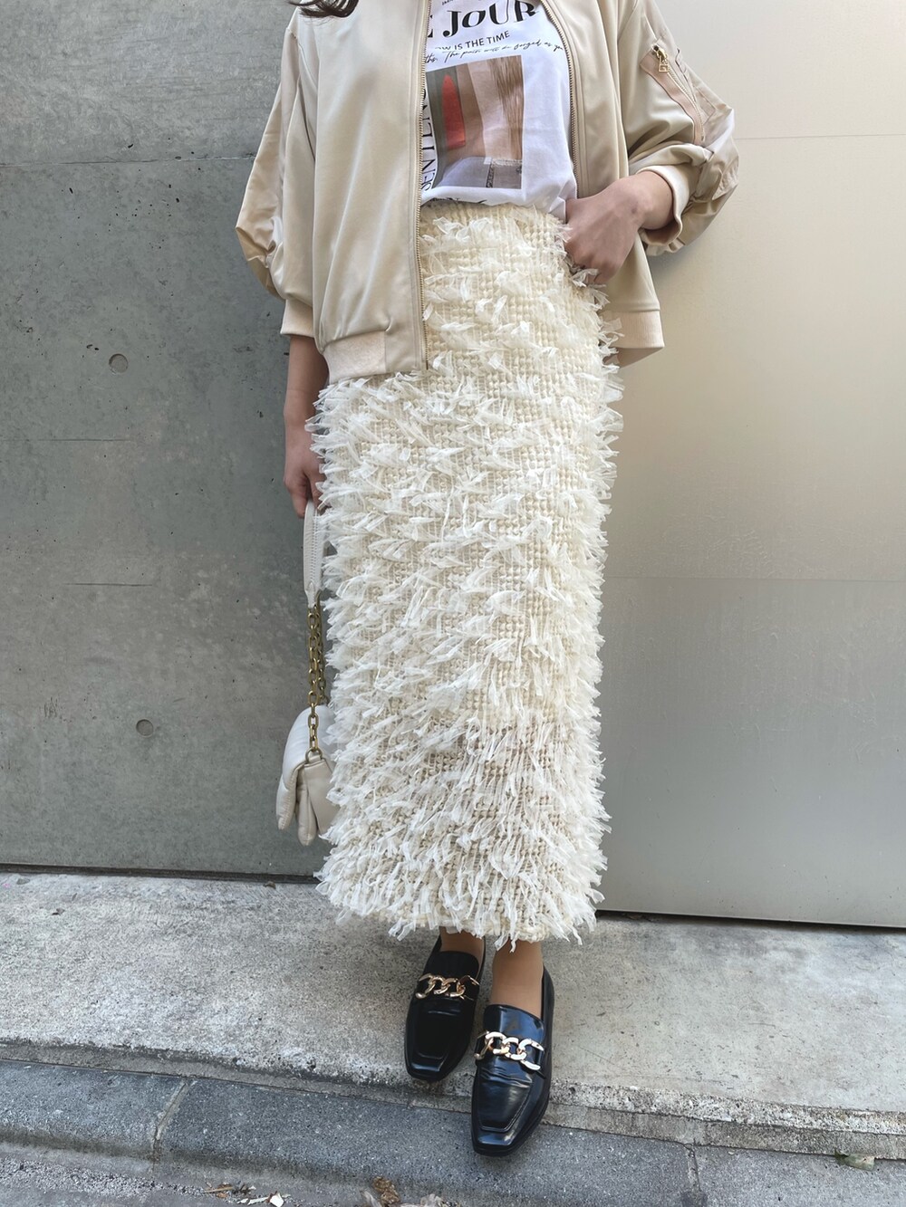 ホワイト系のバッグ、ブラック系のローファー、ホワイト系のスカートを着用したレディースの春コーディネートの4枚目の写真