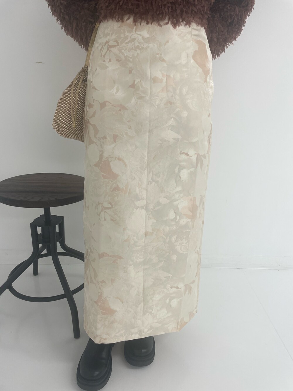 ゴールド系のトートバッグ、ホワイト系のスカート、ブラウン系のTシャツ/カットソーを着用したレディースの冬コーディネートの8枚目の写真