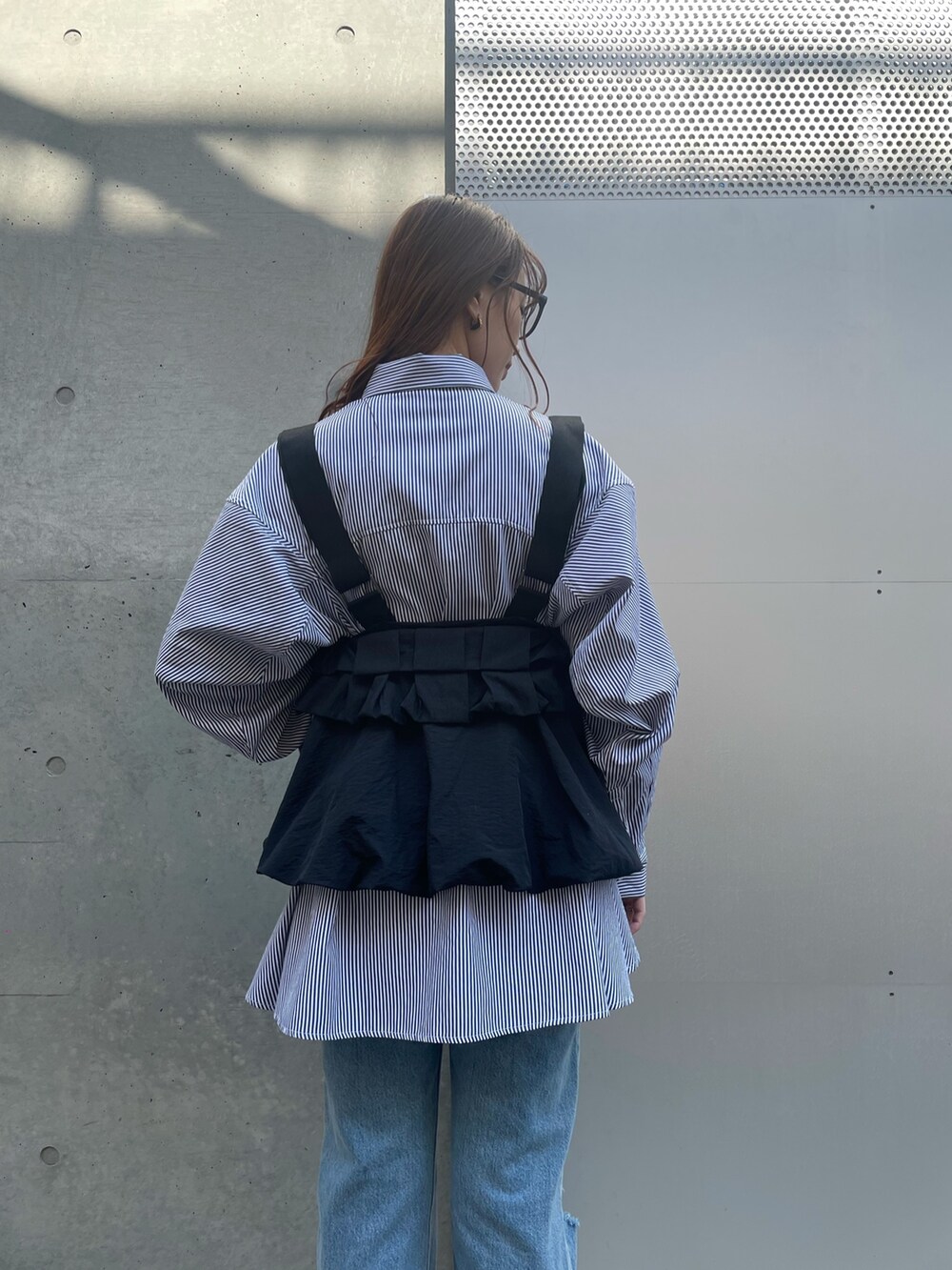 ブルー系のデニムパンツ、ブラック系のローファー、ブラック系のベストを着用したレディースの春コーディネートの3枚目の写真