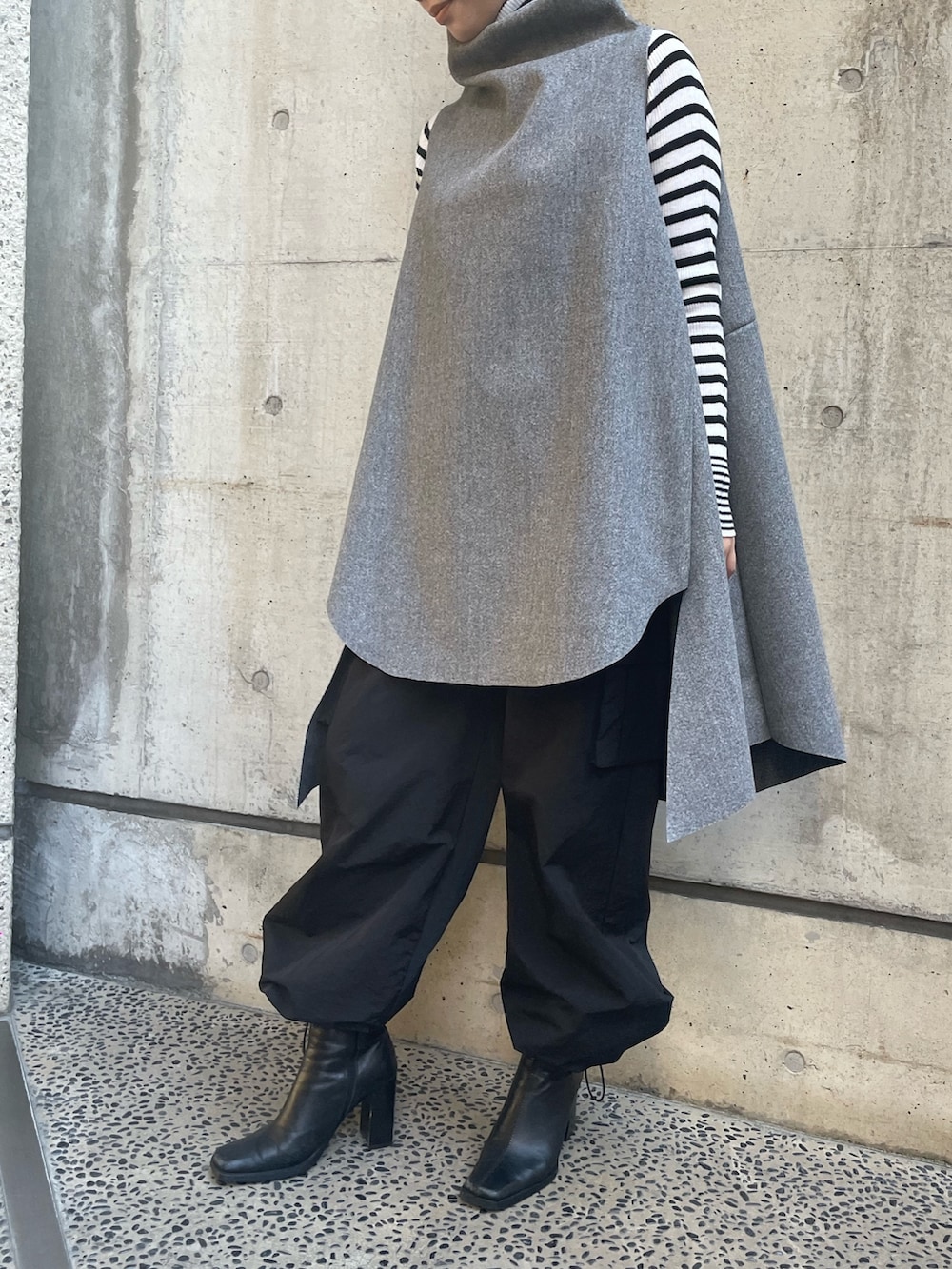 グレー系のベスト、ホワイト系のニット/セーターを着用したレディースの秋コーディネートの2枚目の写真