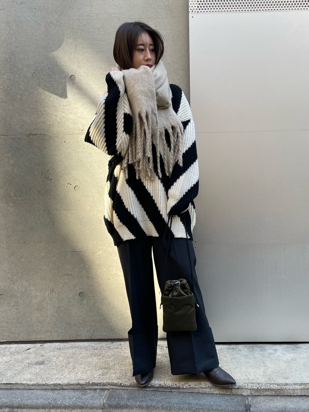 ブラック系のその他パンツ、ブラック系のニット/セーター、ベージュ系のストール/ショールを着用したレディースの冬コーディネートの3枚目の写真