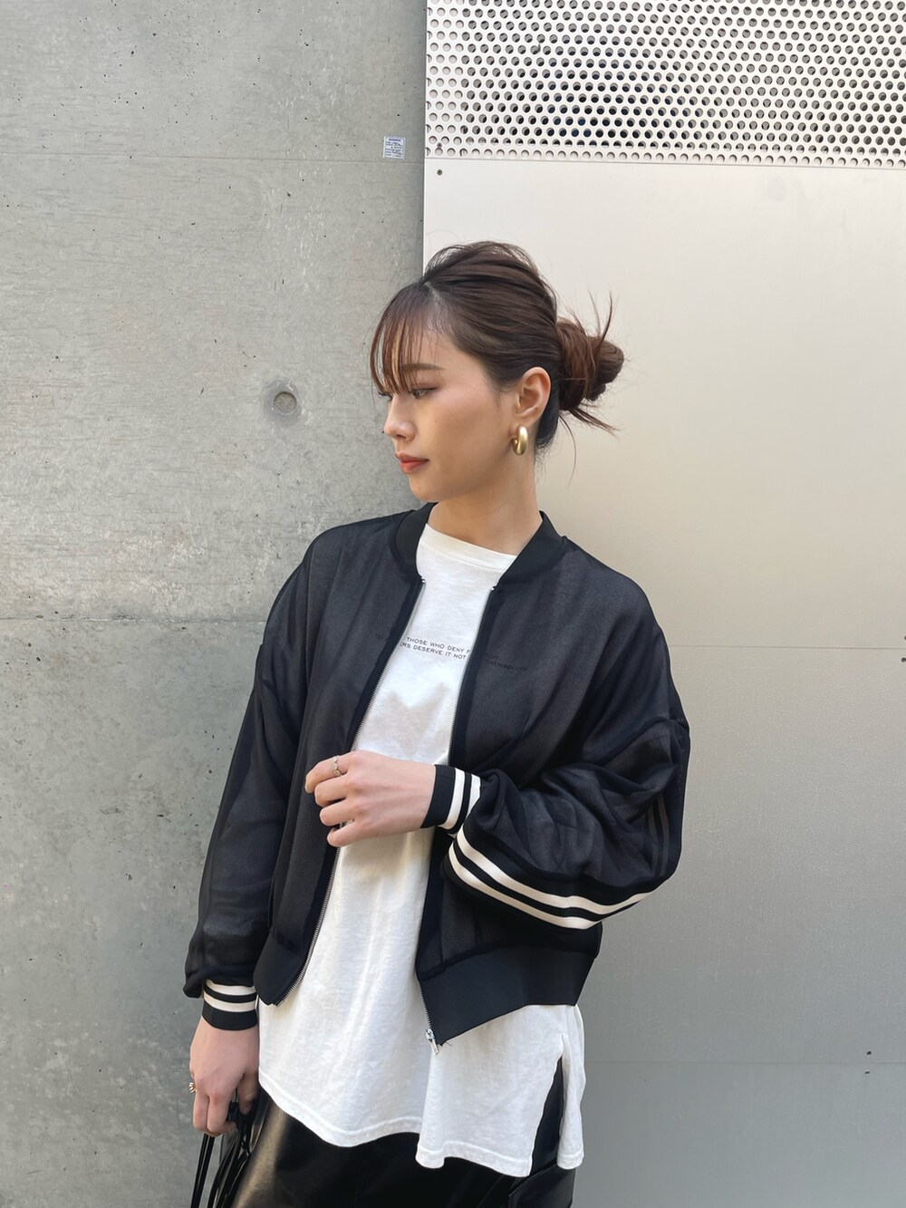 ブラック系のショルダーバッグ、ブラック系のスカート、ブラック系のブルゾンを着用したレディースの春コーディネートの3枚目の写真