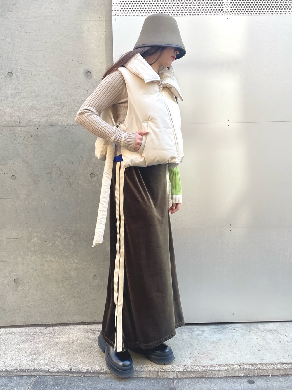 グリーン系のスカート、ベージュ系のニット/セーター、ホワイト系のダウンベストを着用したレディースの冬コーディネートの4枚目の写真