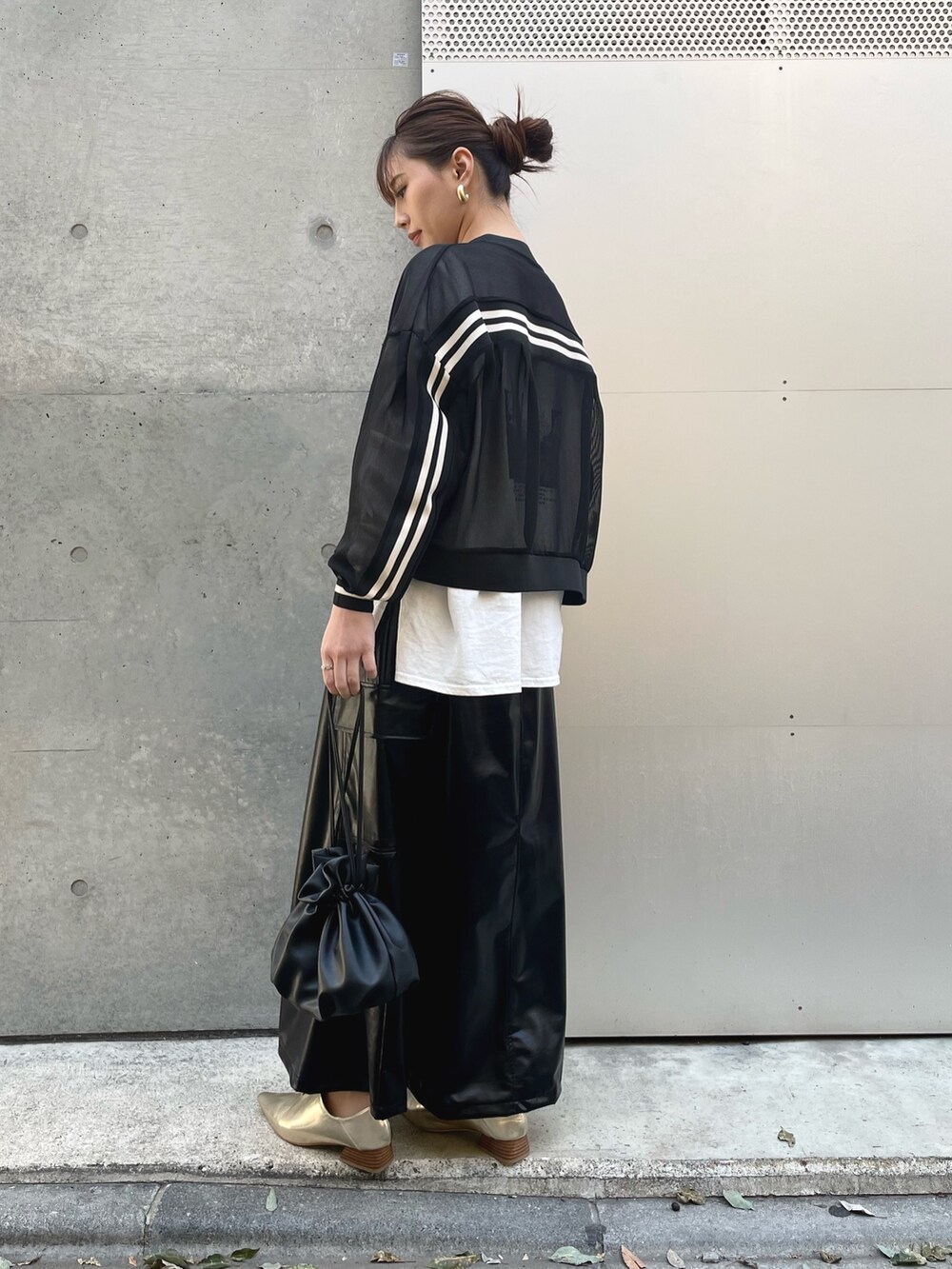 ブラック系のショルダーバッグ、ブラック系のスカート、ブラック系のブルゾンを着用したレディースの春コーディネートの2枚目の写真