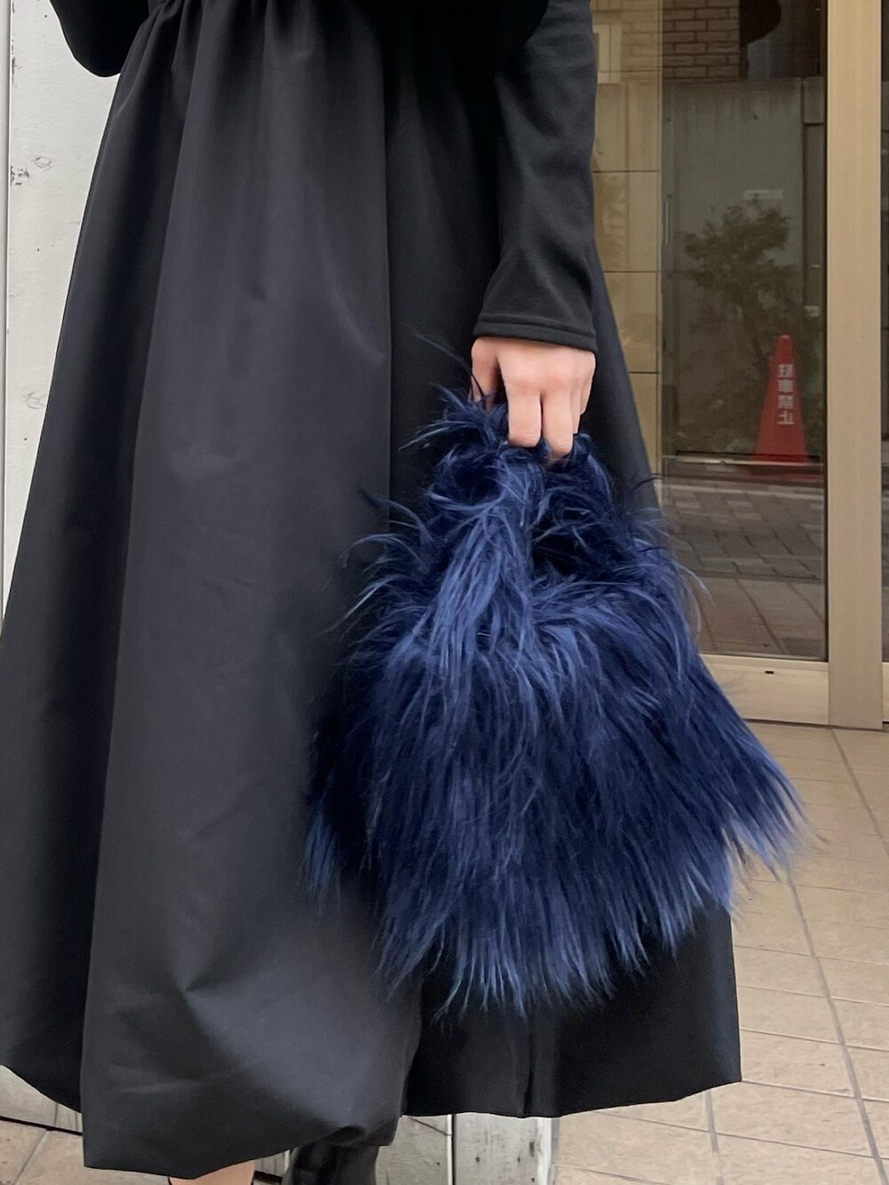 ブルー系のハンドバッグ、ブラック系のワンピース、ゴールド系のピアス（両耳用）を着用したレディースの冬コーディネートの4枚目の写真