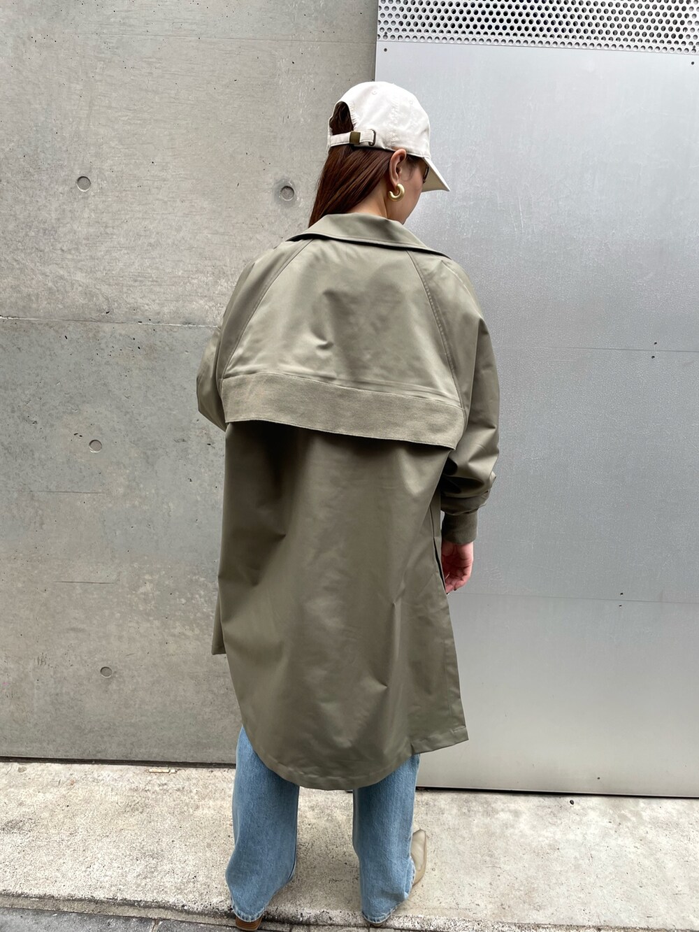 グレー系のスウェット、グリーン系のトレンチコート、ブルー系のデニムパンツを着用したレディースの春コーディネートの2枚目の写真