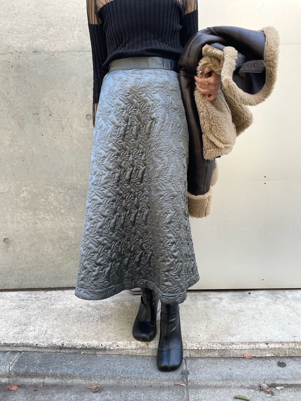 ブラウン系のジャケット/アウター、グリーン系のスカート、ブラック系のニット/セーターを着用したレディースの冬コーディネートの4枚目の写真