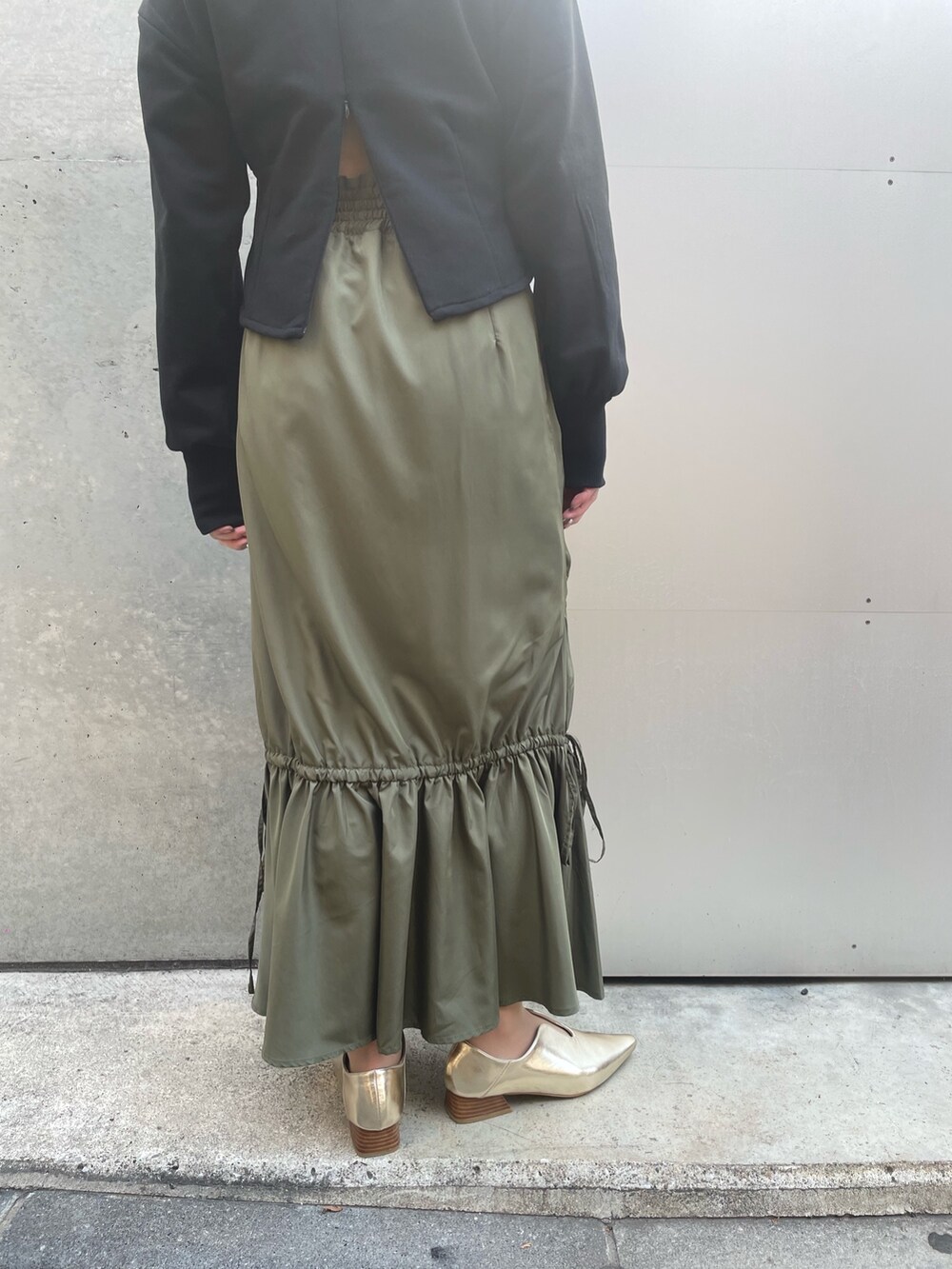 ブラック系のスウェット、グリーン系のスカート、ブラック系のキャップを着用したレディースの春コーディネートの5枚目の写真